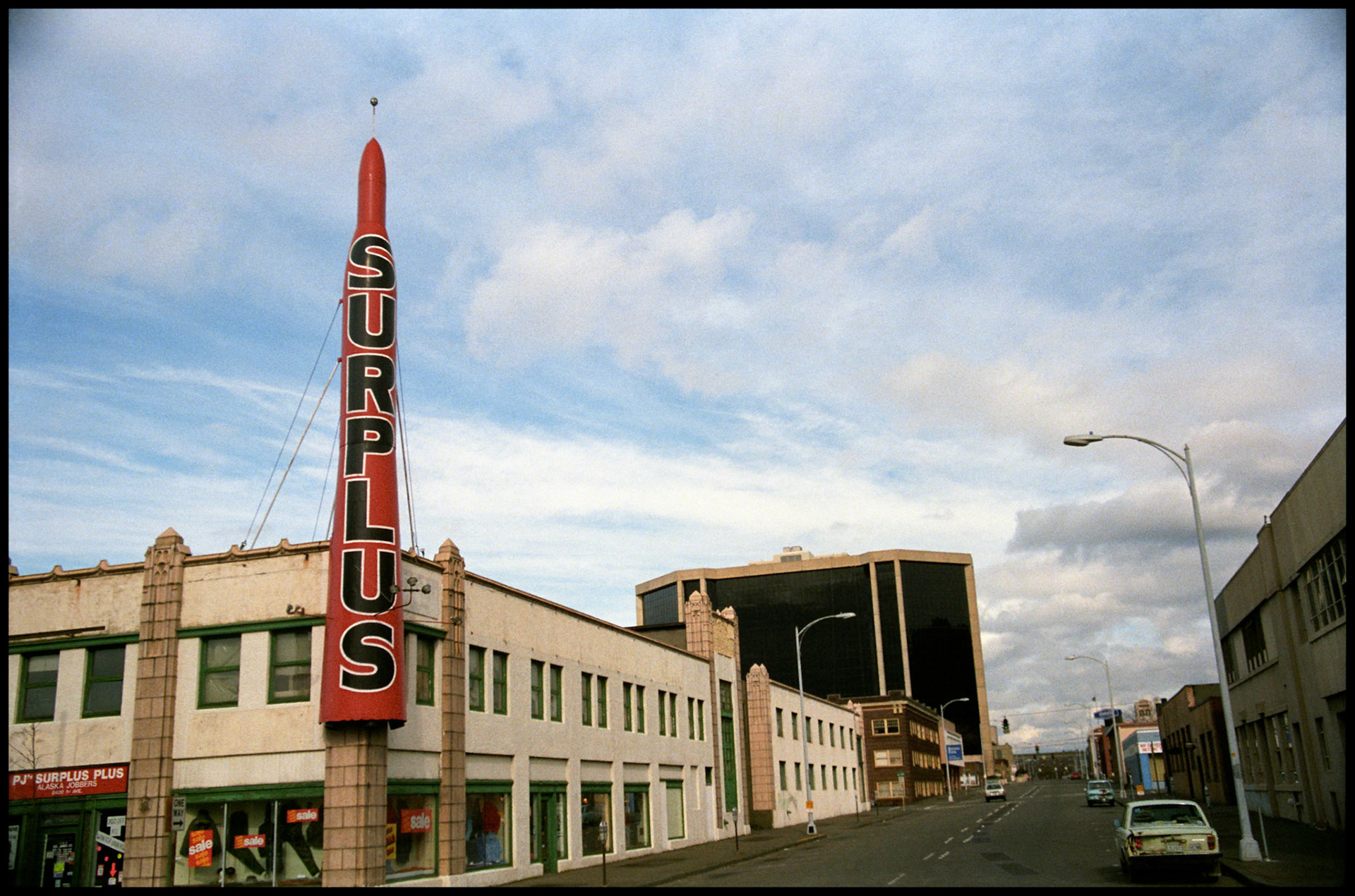 A vintage street scene of a military surplus store at the corner of Third Ave and Battery St in downtown Seattle, Washington USA 1987 (Now the site of Antioch University)