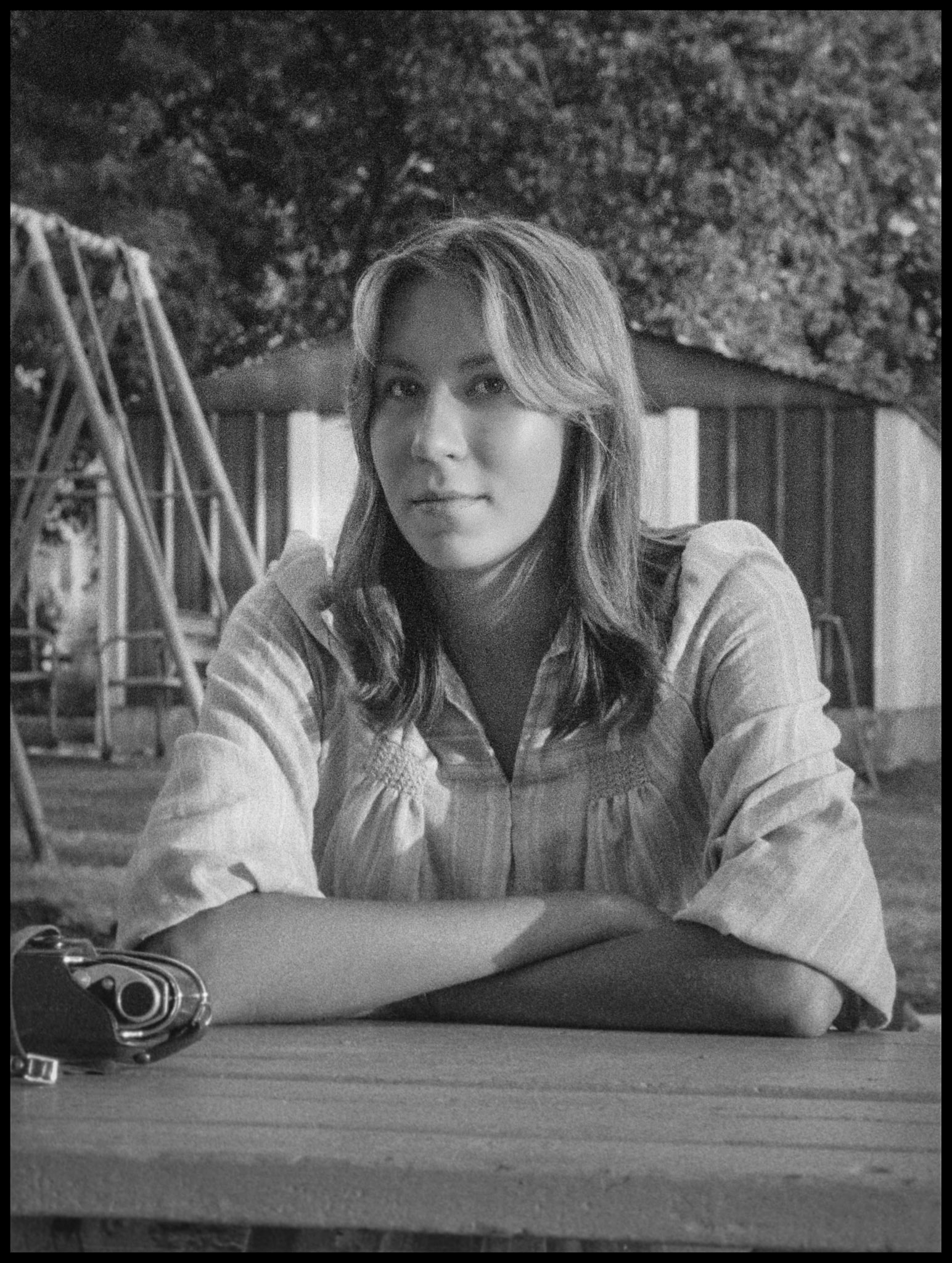 A young woman sitting at a picnic table on a back yard patio with a pensive gaze. Kriksville, Missouri 1976
