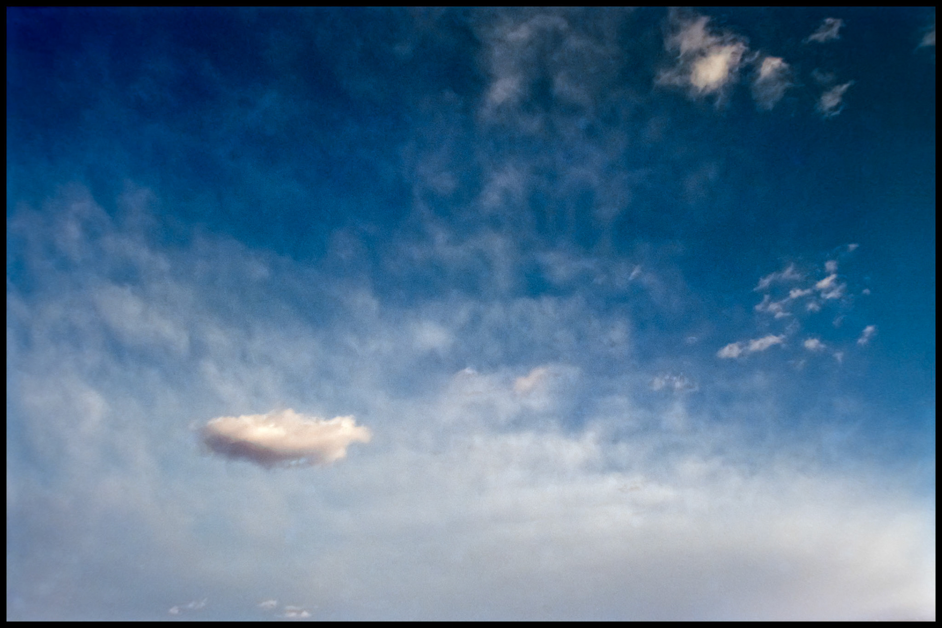 Shimmering silver clouds in a New Mexico sky with a couple little puffy standouts in the foreground. New Mexico USA 1993
