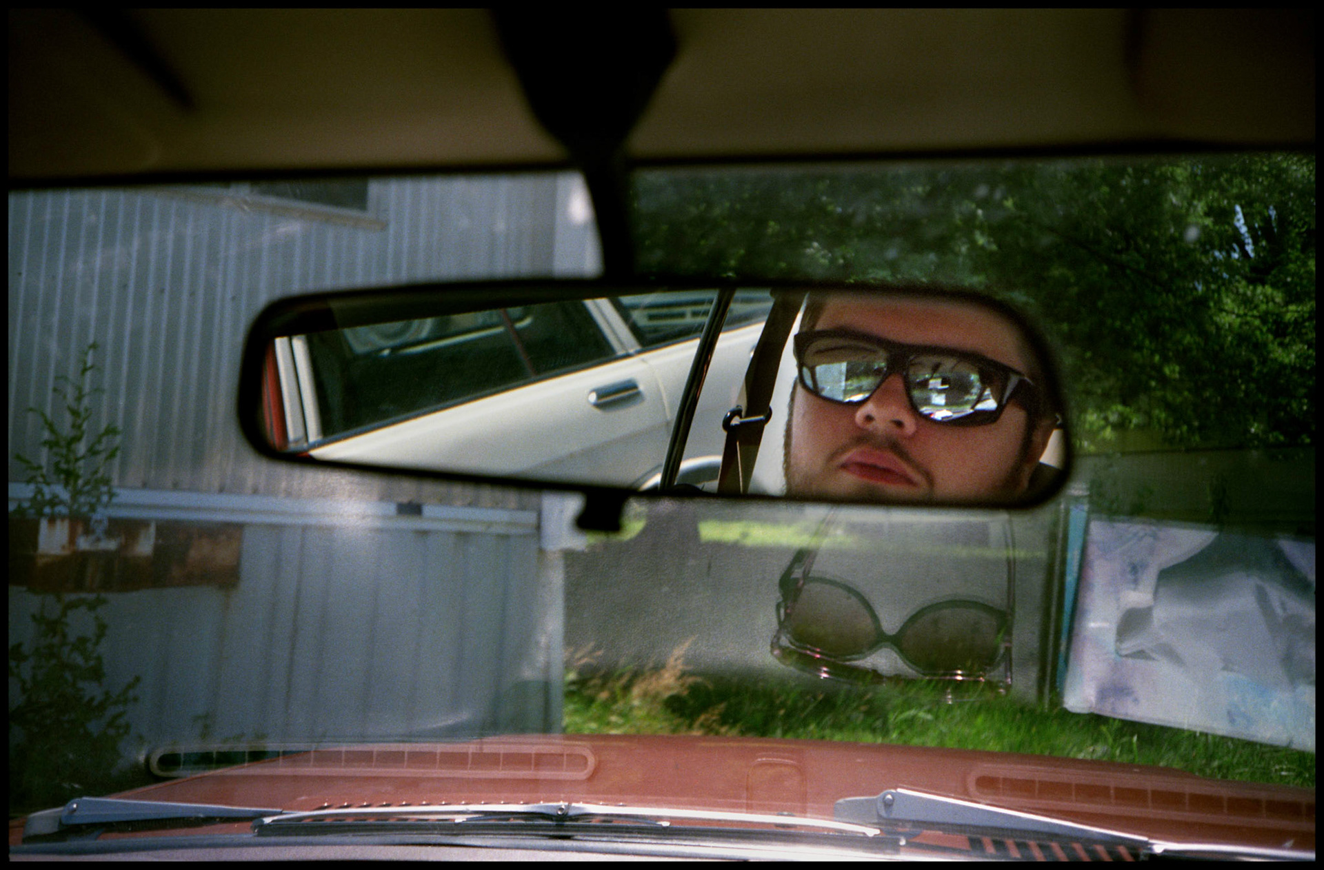 A self portrait in the car mirror wearing reflective sunglasses. Columbia, Missouri 1991