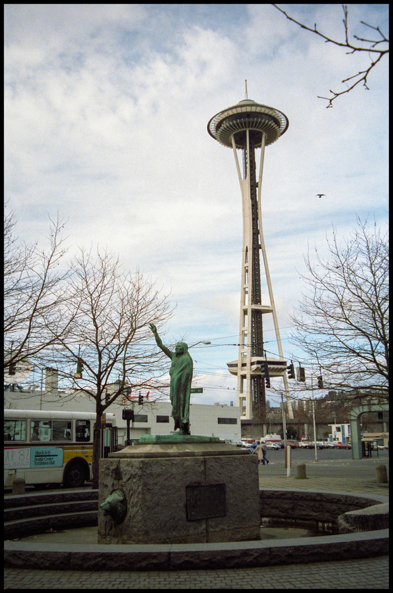 A vintage urban street scene of the Chief Seattle statue in Tilikum Place, Seattle Washington with the Space Needle in the background. Denny Way and Fifth Ave, Seattle Washington USA 1987