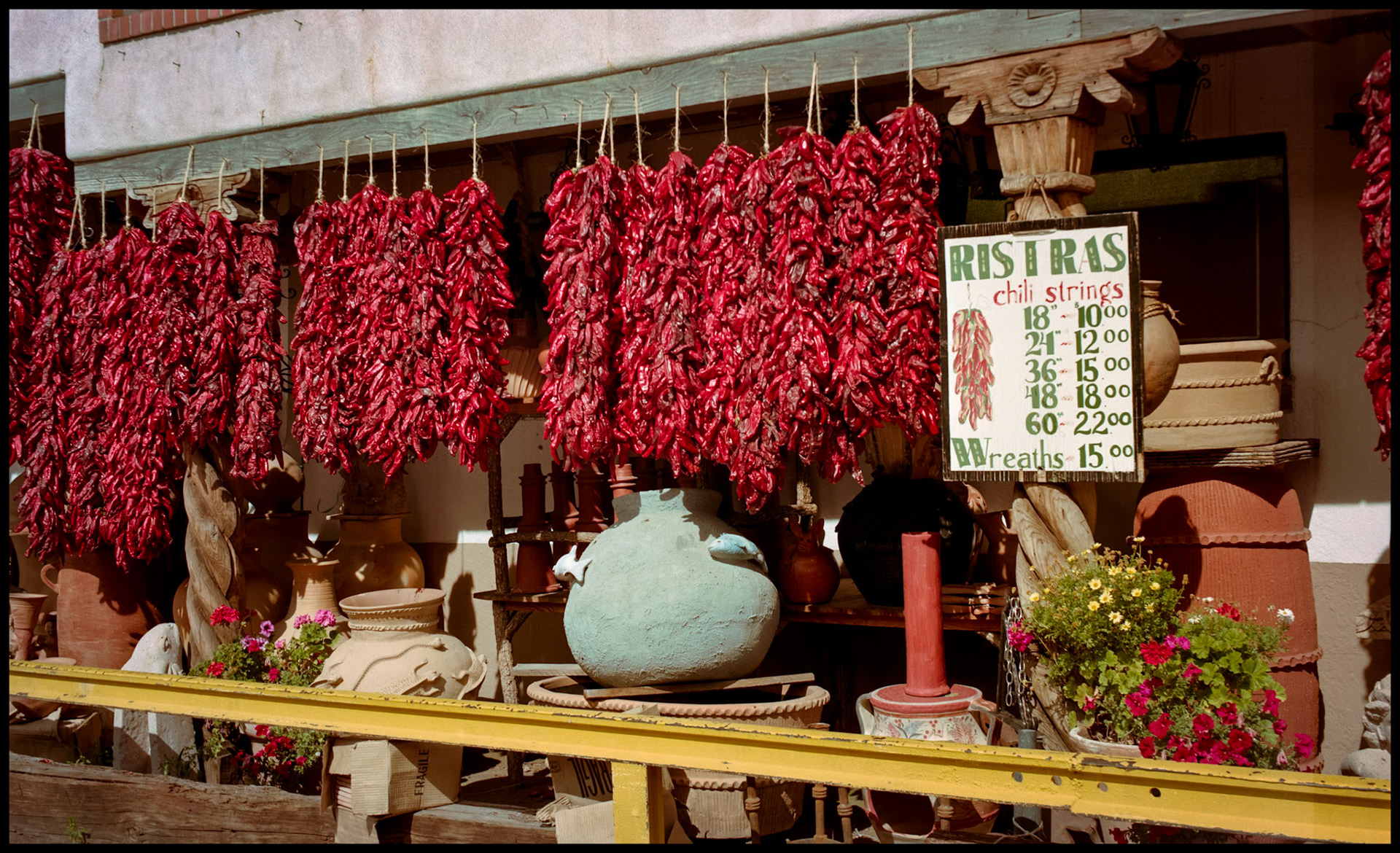 A vintage view of a row of strings of red chili peppers for sale in a public market in Santa Fe, New Mexico USA 1993