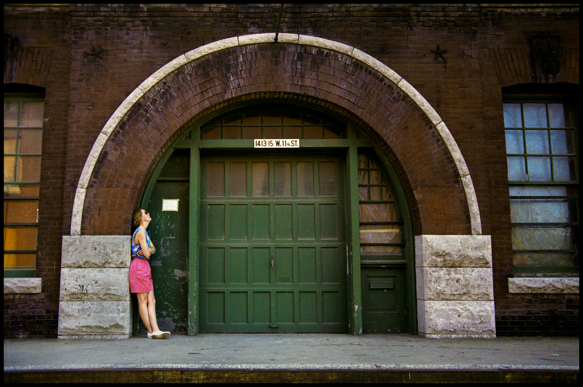 A woman leaning against an arched entryway of a commercial buidling in the industrial area of the West Bottoms, Kansas City, Missouri. 1990