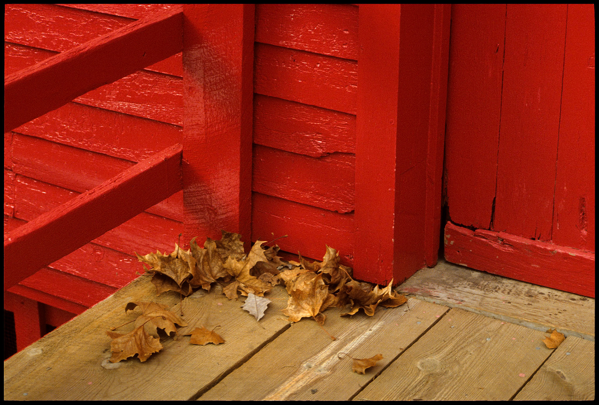 A geometric study of the bright red hand rails and building with some fallen Autumn leaves on the walkway at Alley Spring Mill near Eminence, MO in the Ozark mountains. 1988