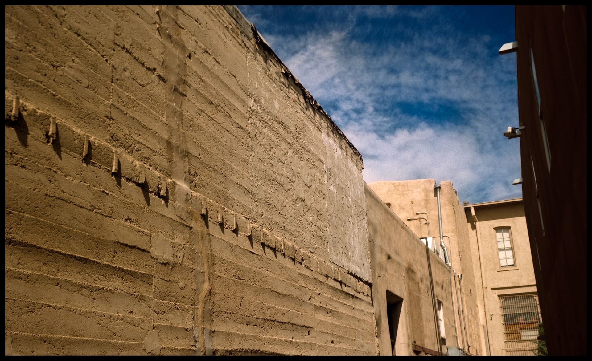 A detail view of an alley brick wall in downtown Santa Fe that butts up to an adobe wall. A study in line, texture and color. Part of my New Mexico Light and Colorado Heights series from a trip in 1993.