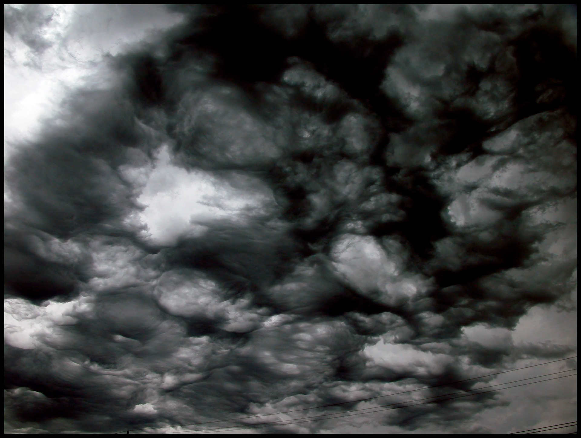 Menacing looking storm clouds with cirular openings of light shining through resembling a face.
