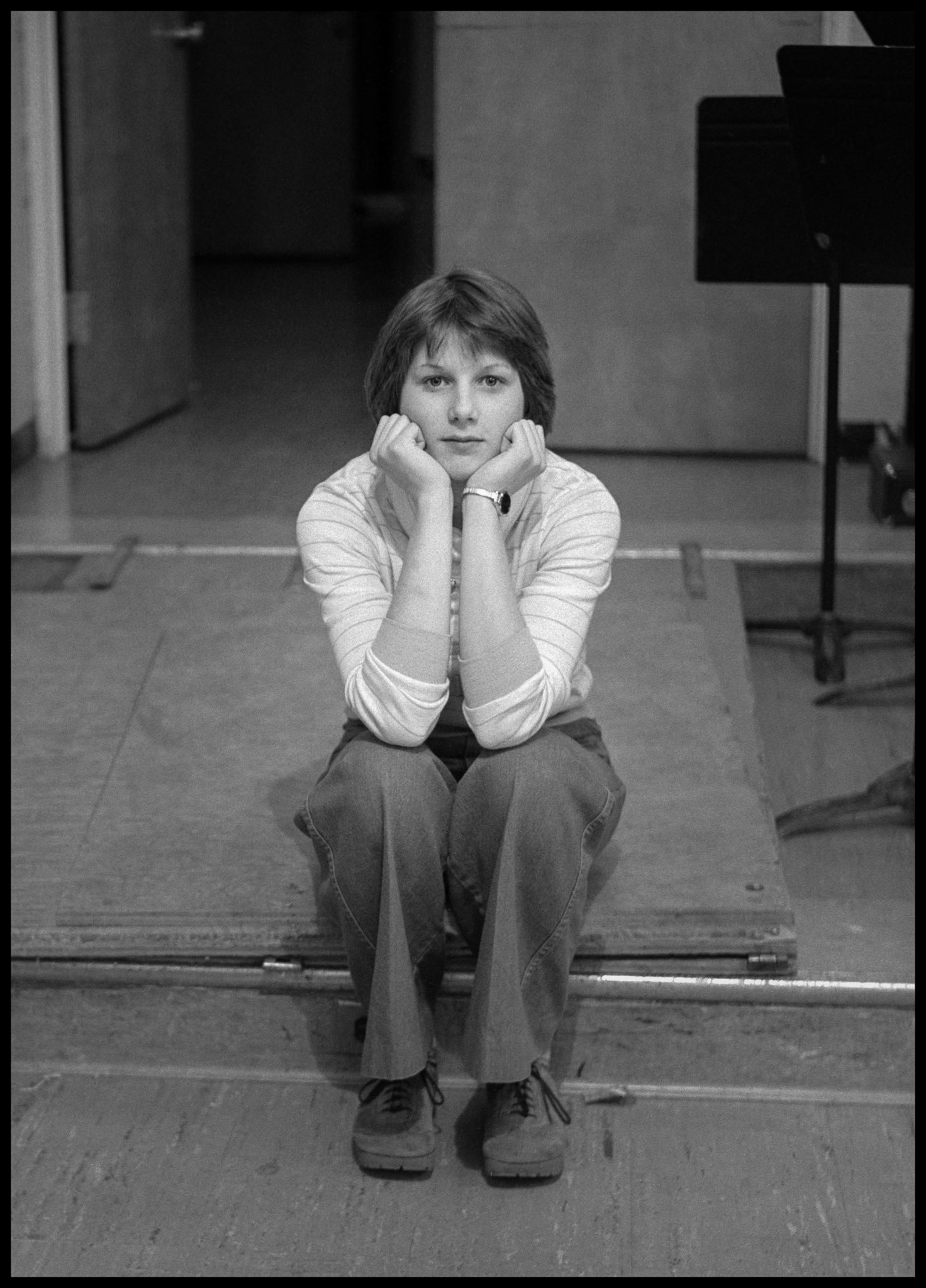 A 1970's vintage image of a young woman sitting on the edge of a music room step, head in hands, with an intent expression. Kirksville, Missouri 1978