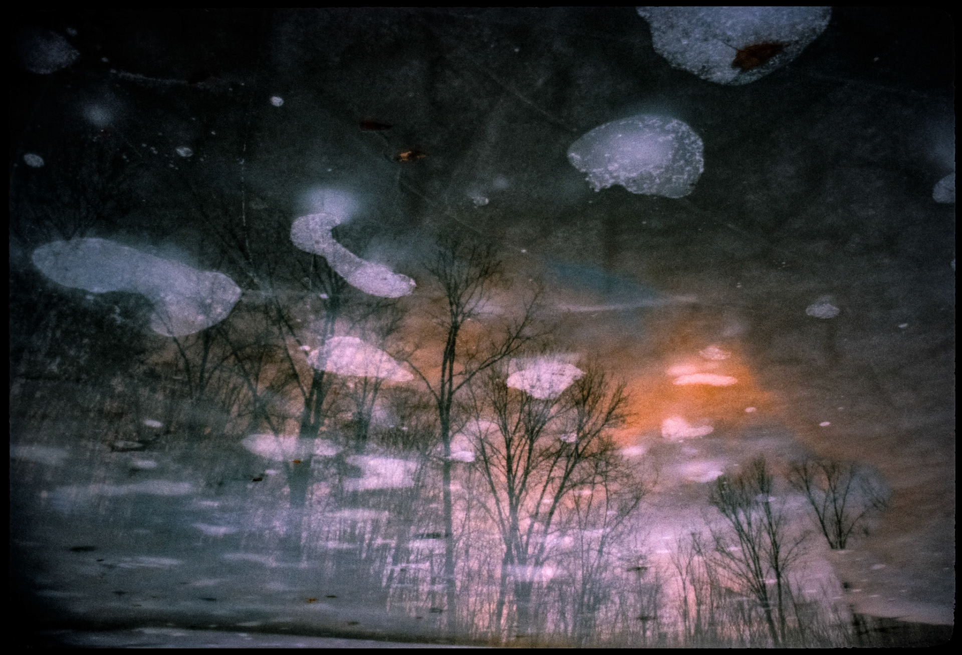 A Missouri winter scene of a sunset and forest reflection in melting ice. The image has been inversed to give the initial illusion that the forest is not a reflection. Thousand Hills State Park, Kirksville, Missouri 1981