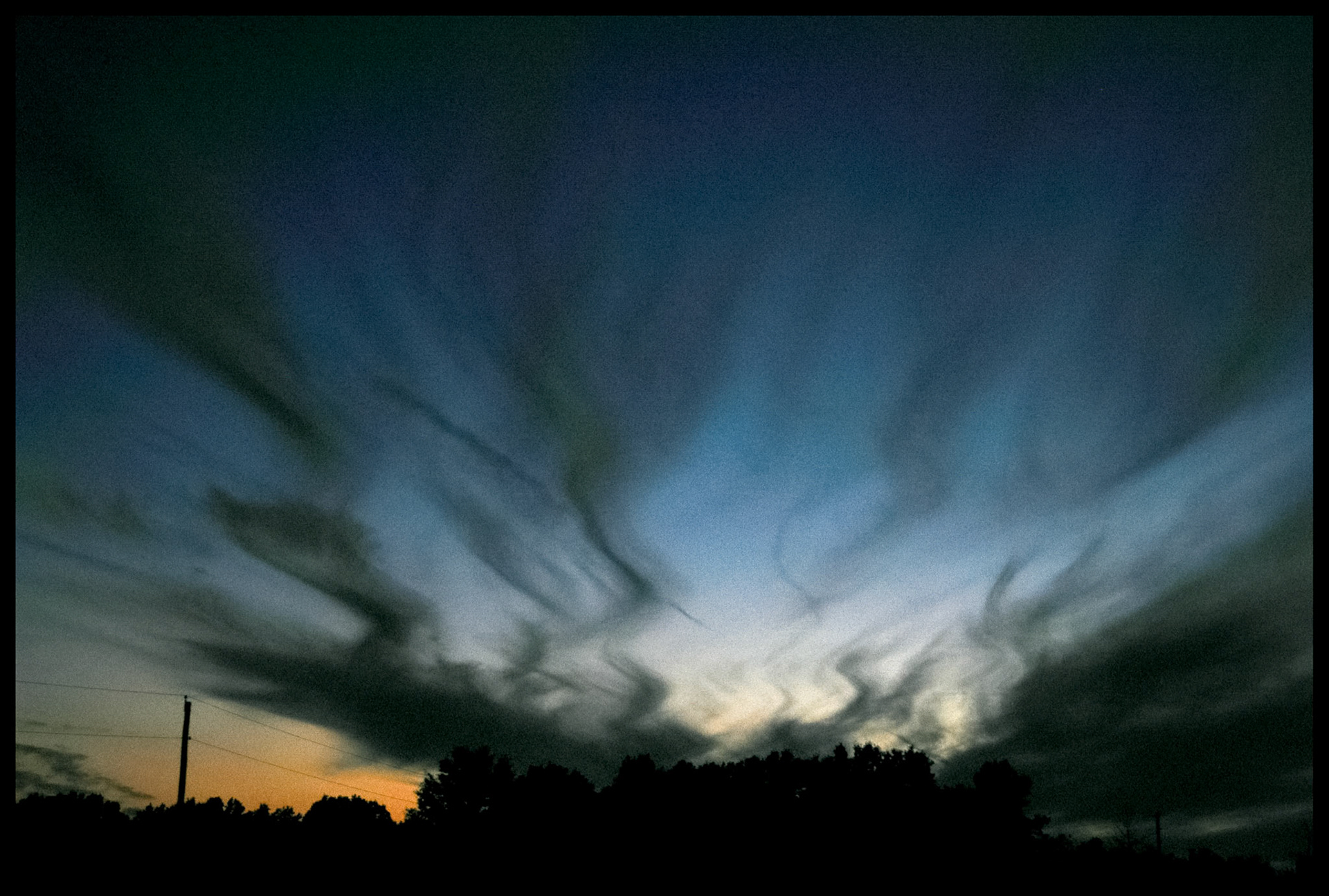 Wispy clouds silhouetted by the dusk sky just after sunset still holding on to the contrasting blue and orange colors before last light. Near Renick, Missouri, 2005