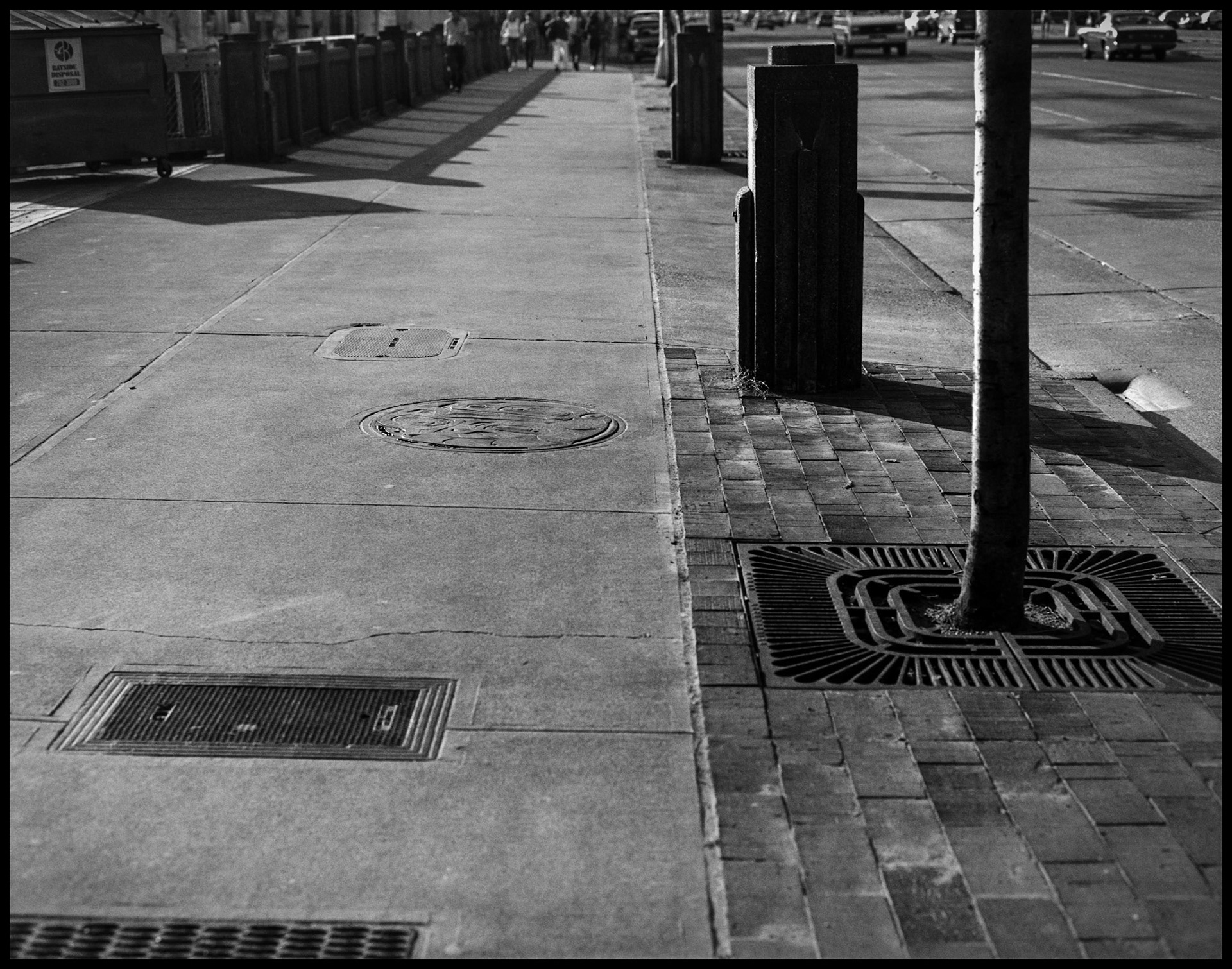 A vintage black and white street scene of various sidewalk grates and interesting shadows near the Seattle waterfront. Seattle Washington USA 1987