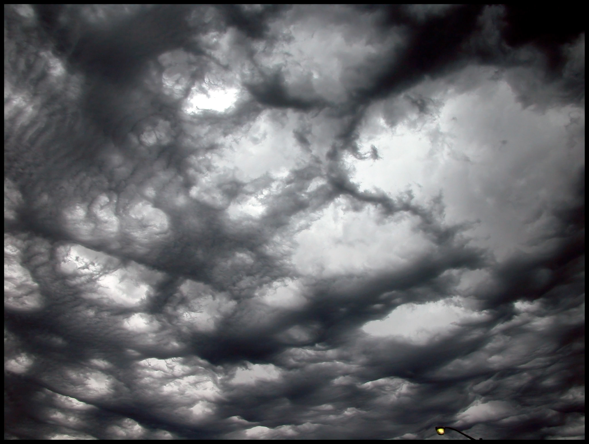 Menacing looking storm couds with circular openings of light shining through.
