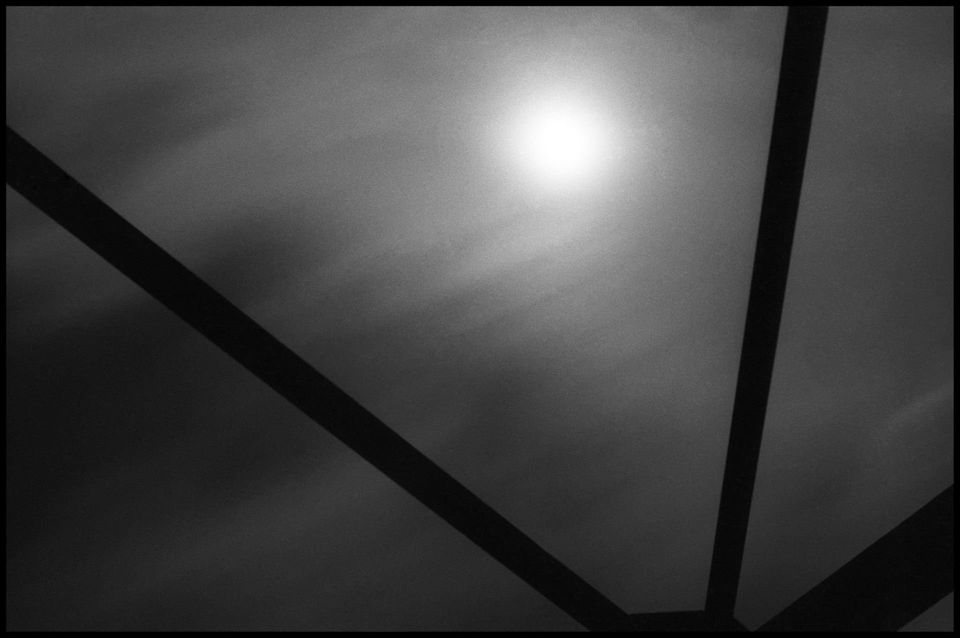 The bright glow of the moon breaking through the evening mist shot through the silhouetted pillars of an old iron bridge. Youngstown, Missouri. 1977