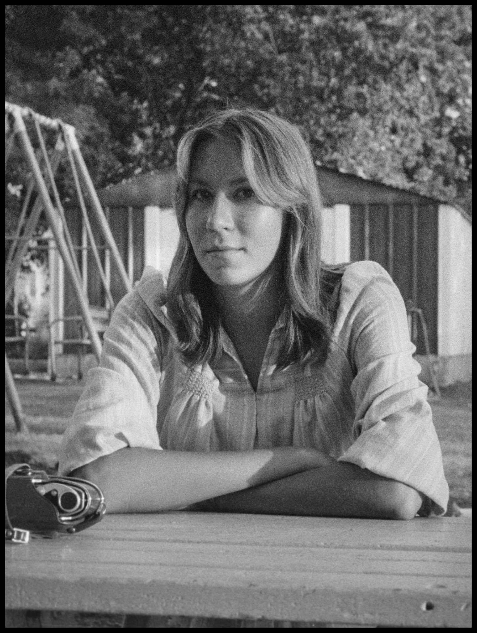 A young woman sitting at a picnic table on a back yard patio with a pensive gaze. Kriksville, Missouri 1976