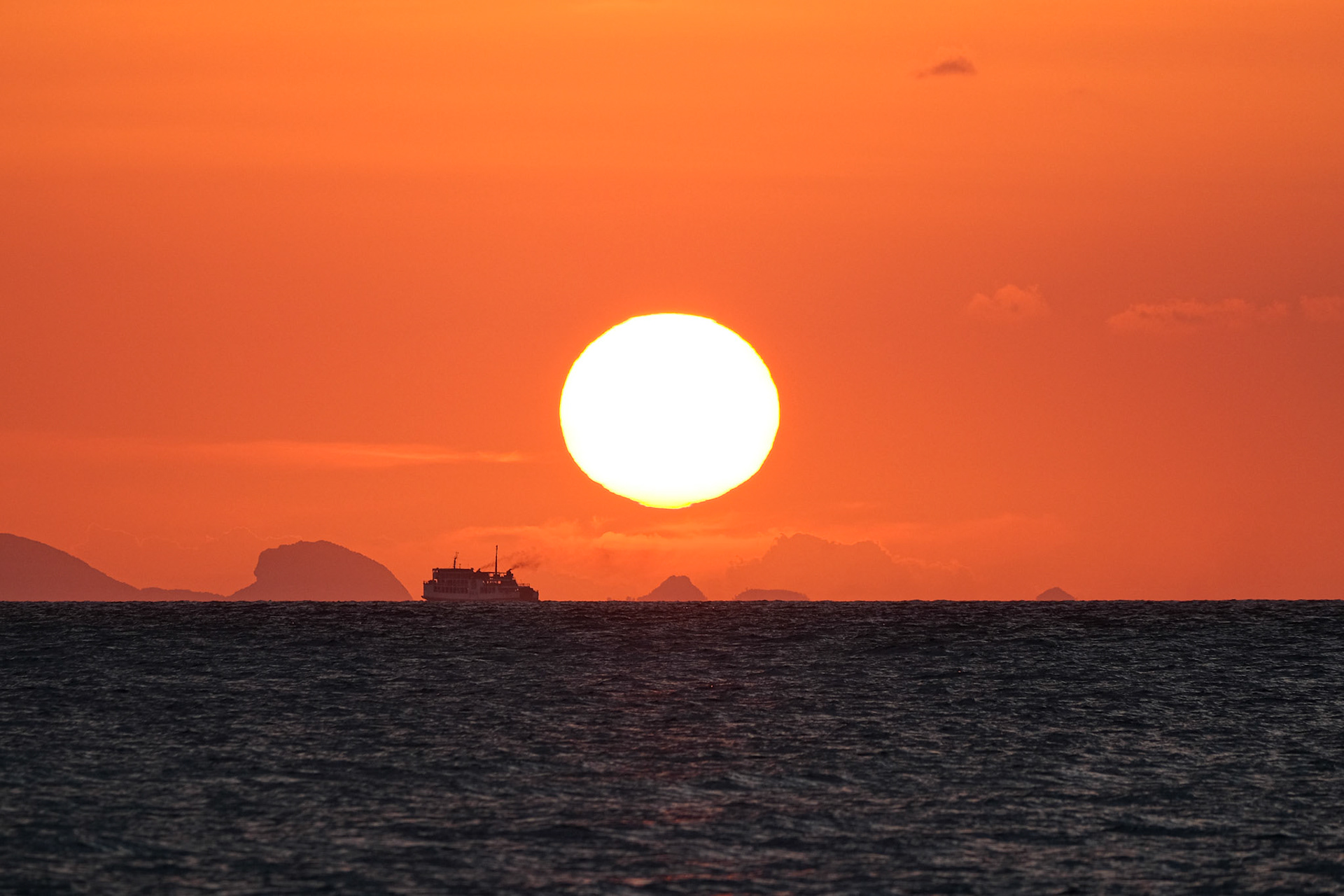 A boat passes under the sun at sunset – Koh Samui, Thailand