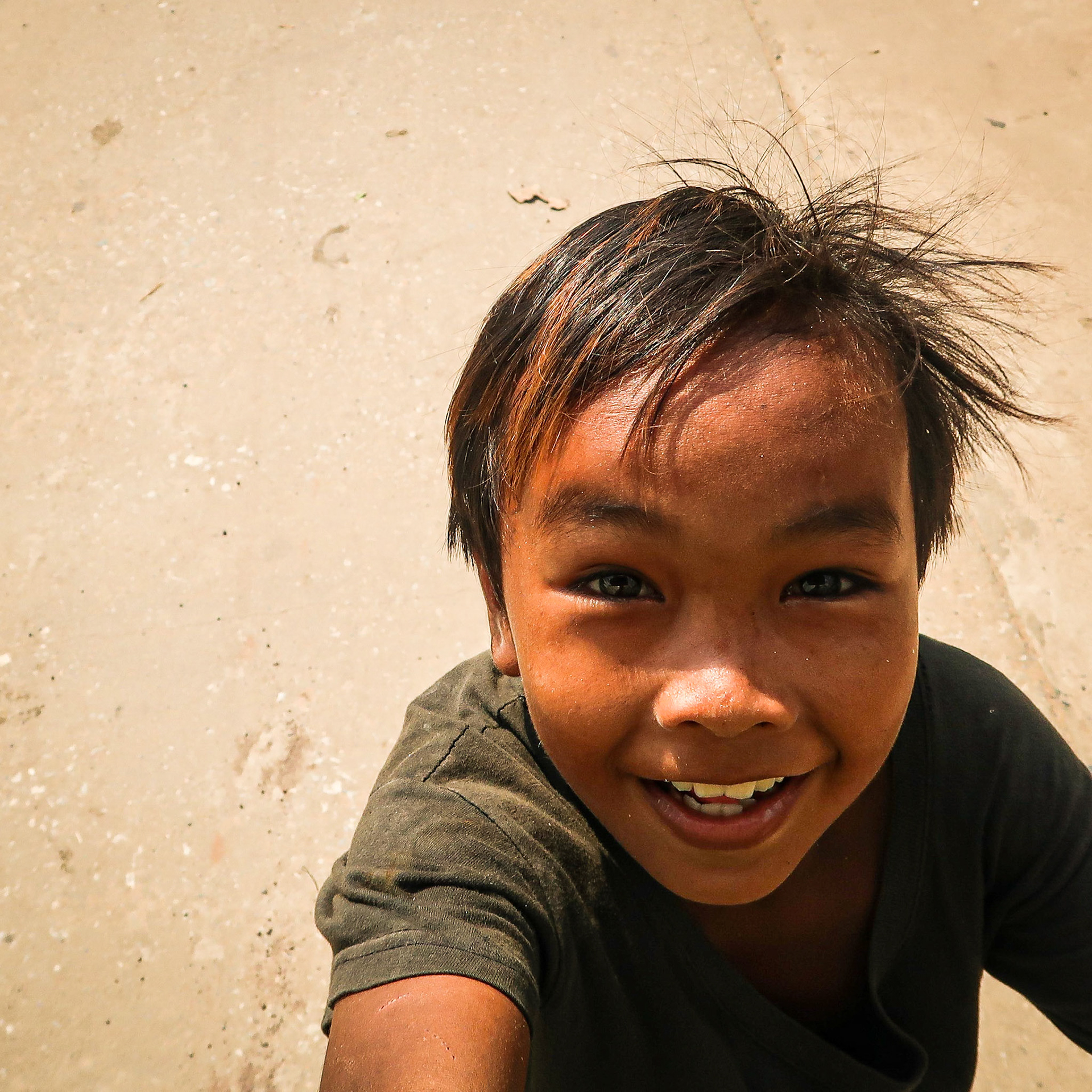 A young boy chases a tuk tuk – Kampot, Cambodia