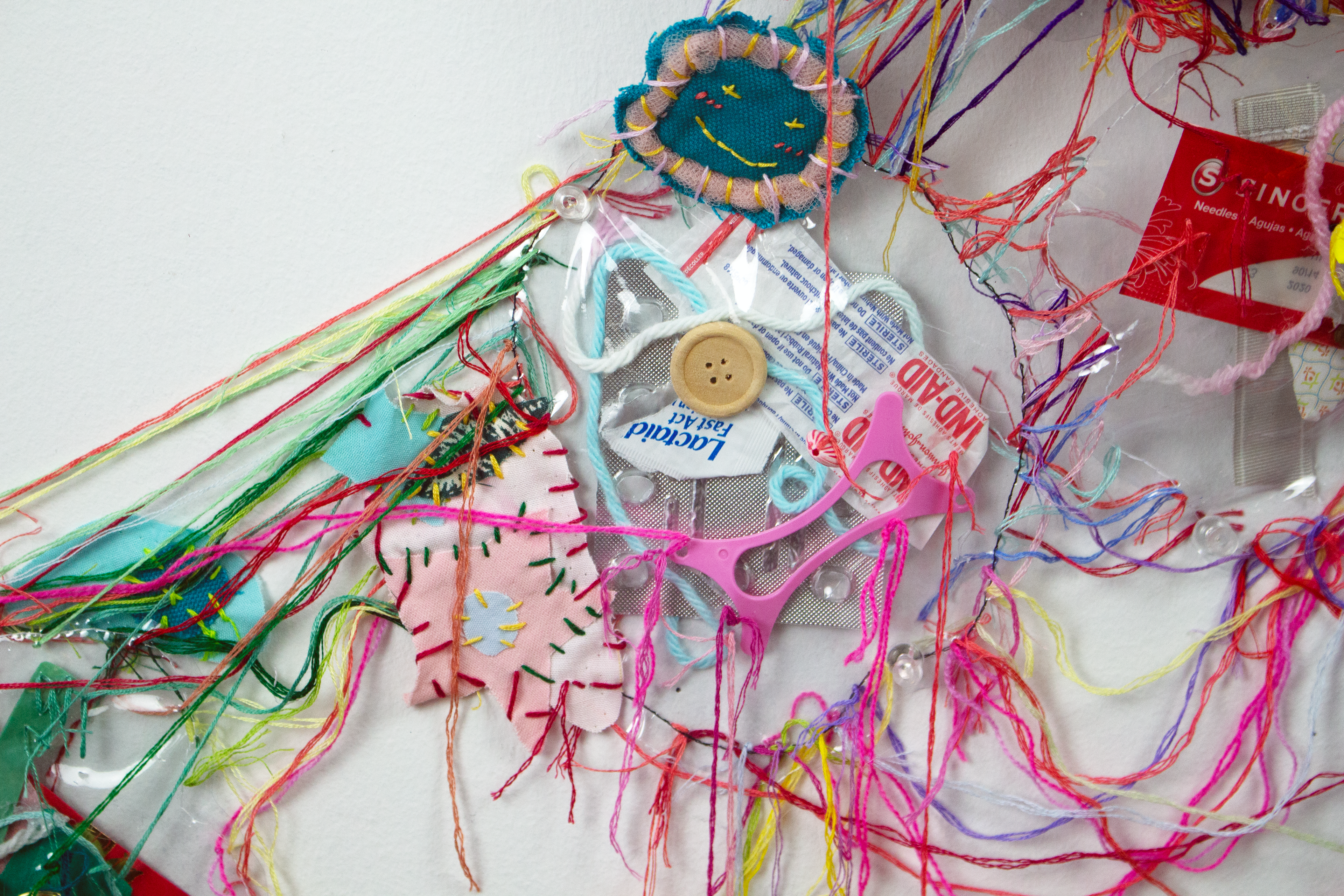 Found items (receipts, cards, wrappers, flyers, paper, etc)  encased in vinyl, thread, fabric, yarn, origami, buttons, beads. Machine and hand sewn.
