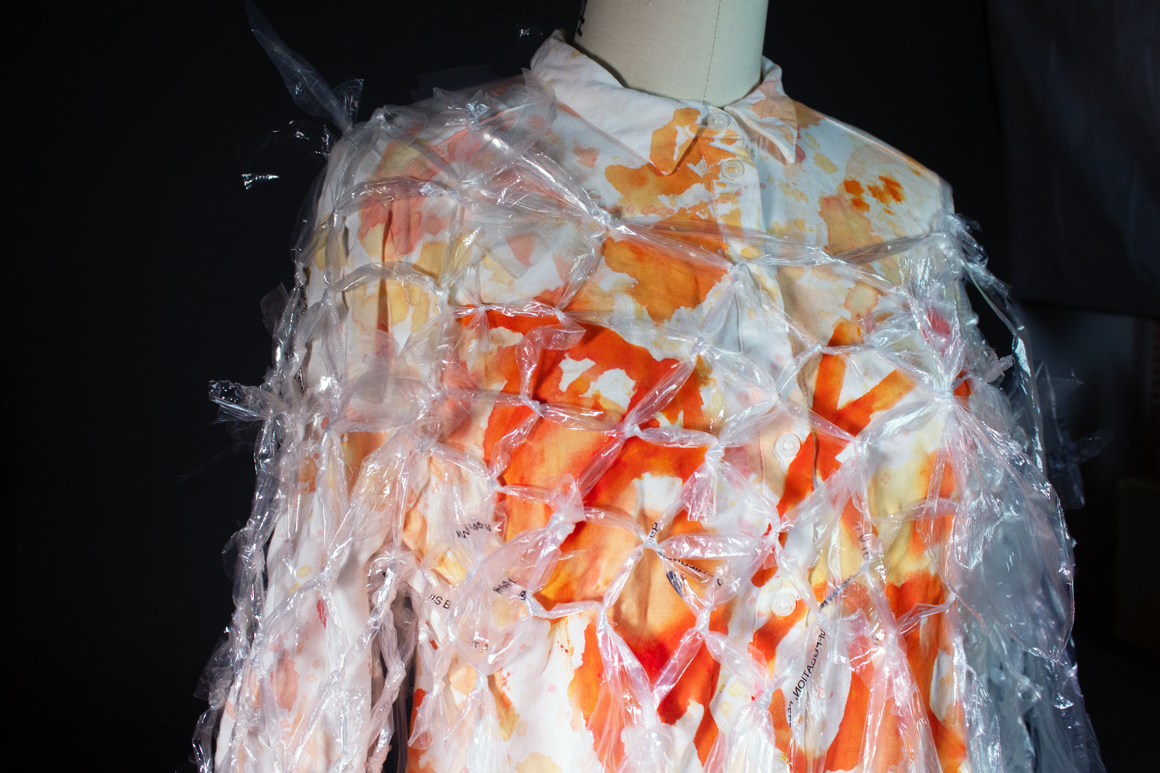 A white outfit accented by plastic and oranges. I used waste from my clothing retail job to create a woven top, and a vinyl tablecloth and the leftover food waste from my home’s kitchen to create a quilted skirt. The result is a commentary on overconsumption in today’s society.