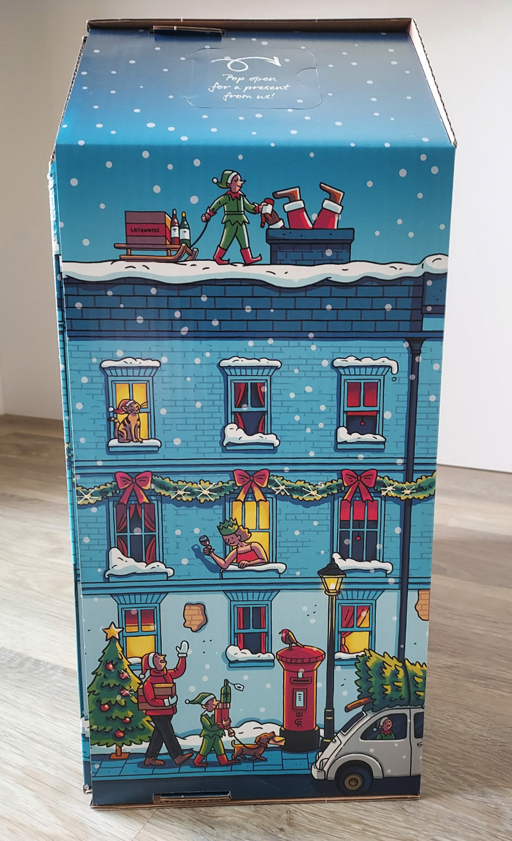 Photo of an advent calendar box, with an illustration of a snowy street with Christmas decorations and people