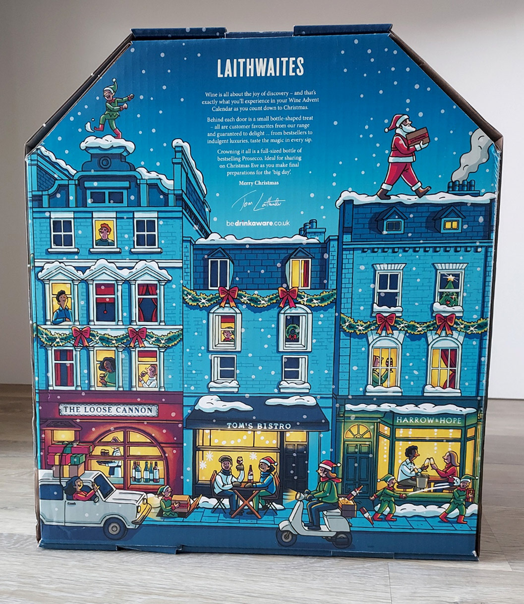 Photo of an advent calendar box, with an illustration of a snowy street with Christmas decorations and people