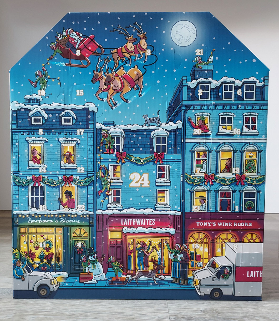 Photo of an advent calendar box, with an illustration of a snowy street with Christmas decorations and people