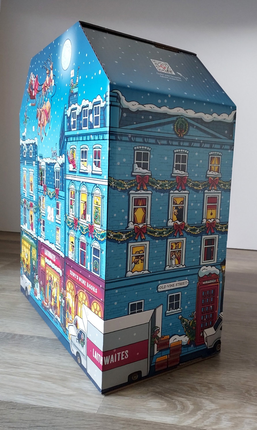 Photo of an advent calendar box, with an illustration of a snowy street with Christmas decorations and people