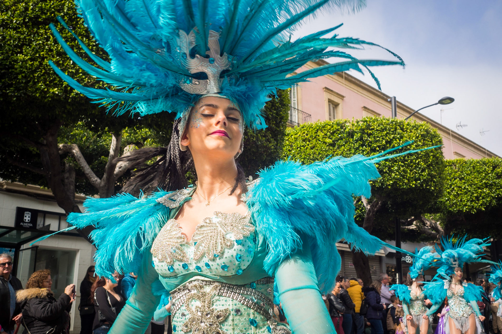Beautiful girl dancer in blue carnival dress with blue feathers at The Almeria Carnival Parade , Spain.