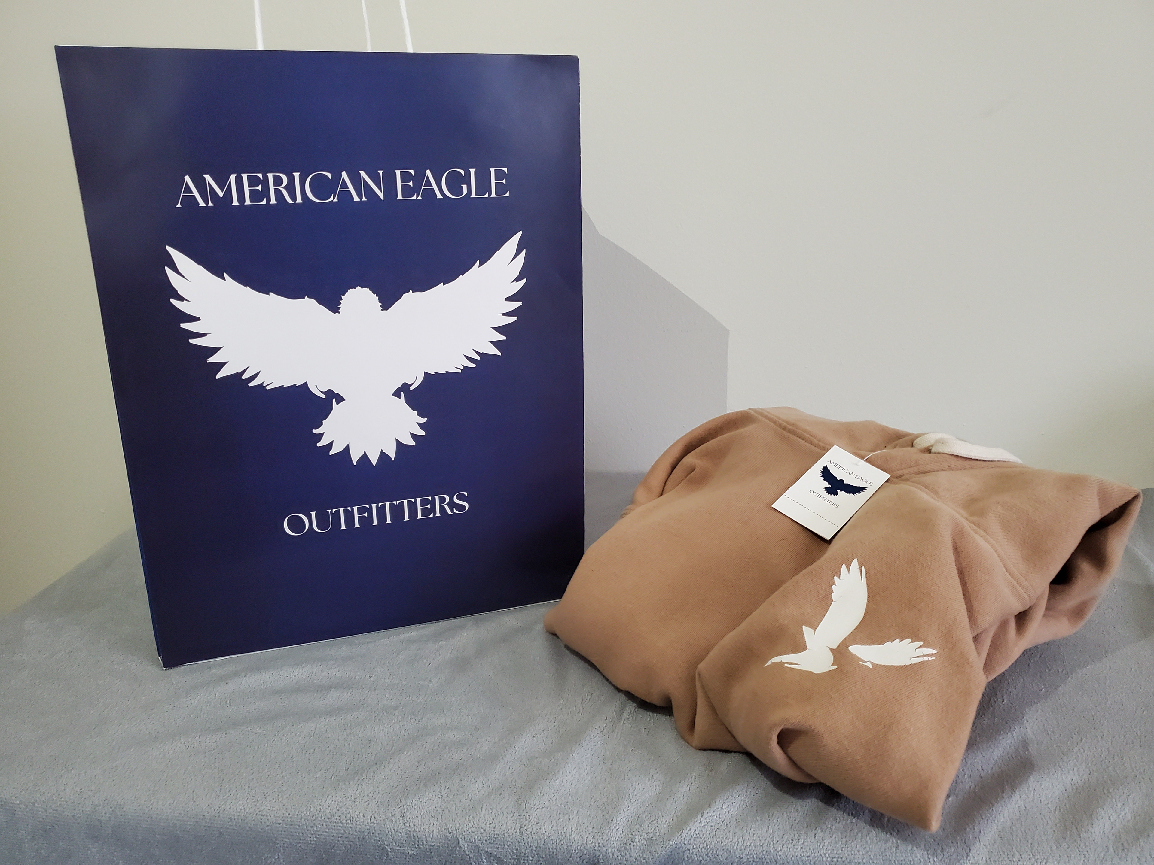 Shopping bag accompanied with an American Eagle sweatshirt with designed price tag attached.