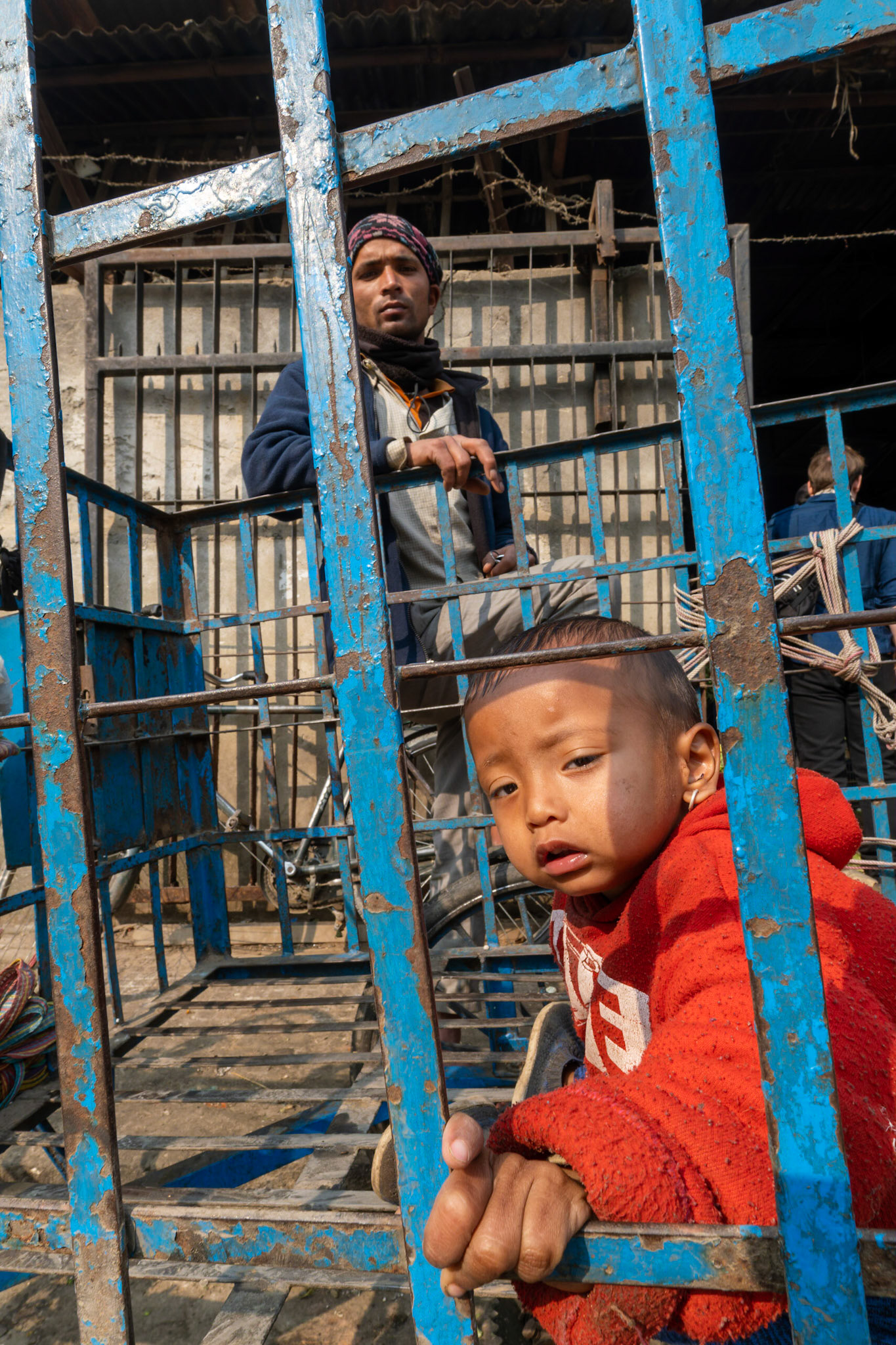Cet enfant n'est ni détenu ni prisonnier, il préfère simplement le confort sommaire de la charette de son père plutôt que de marcher à pied.