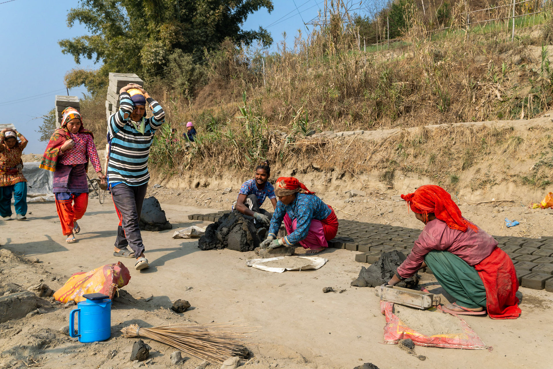 Les porteurs traversent parfois des parcelles où des ouvriers moulent de nouvelles briques. Il faut alors bien faire attention où mettre ses pieds.