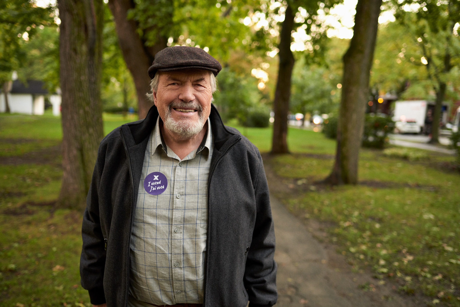 an older man with a beard laughs while walking in a montreal parc