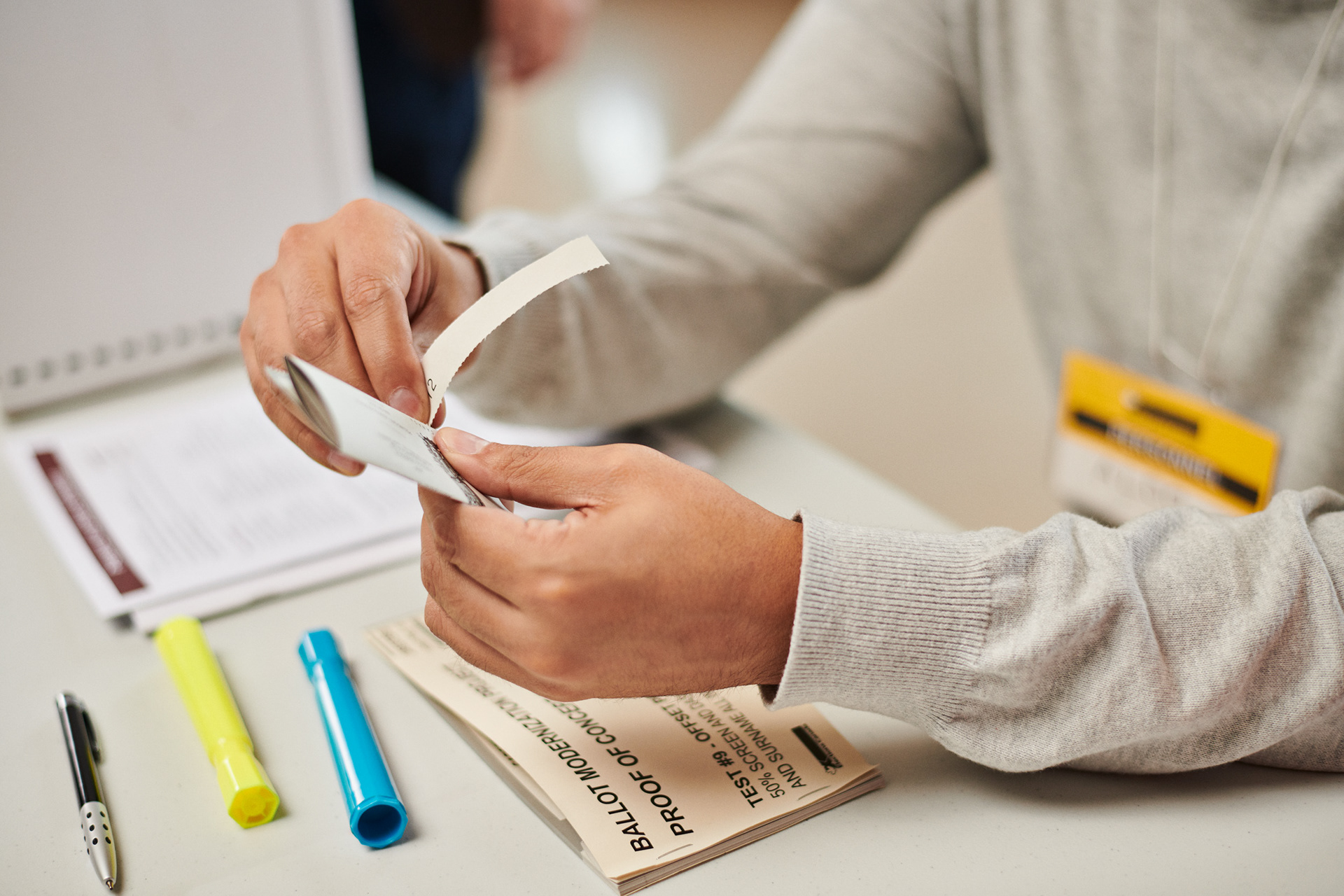 female hands tearing a ballot in oder to then put into a box