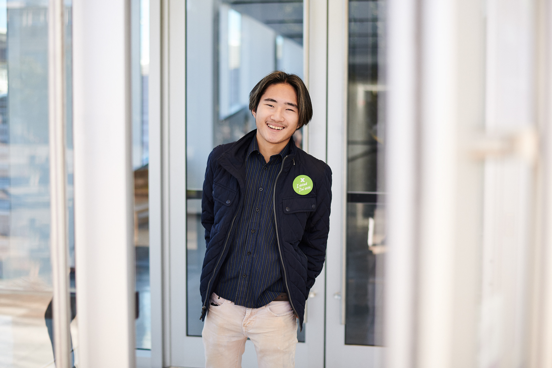 a young asian man laughing as he walks through some doors