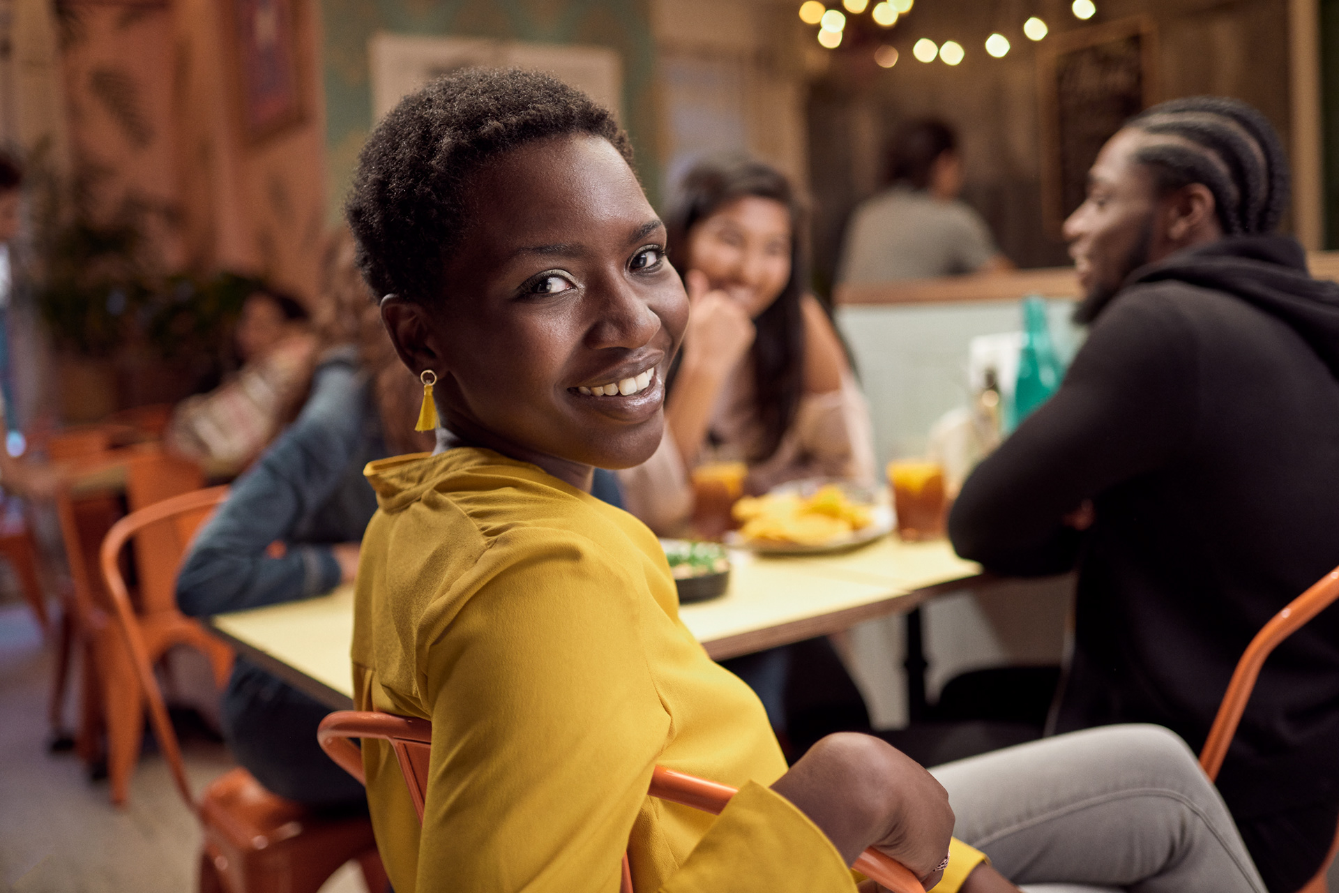 girl sitting looking back at the camera in an editorial style pose with a slight smile while her friends continue to chat.