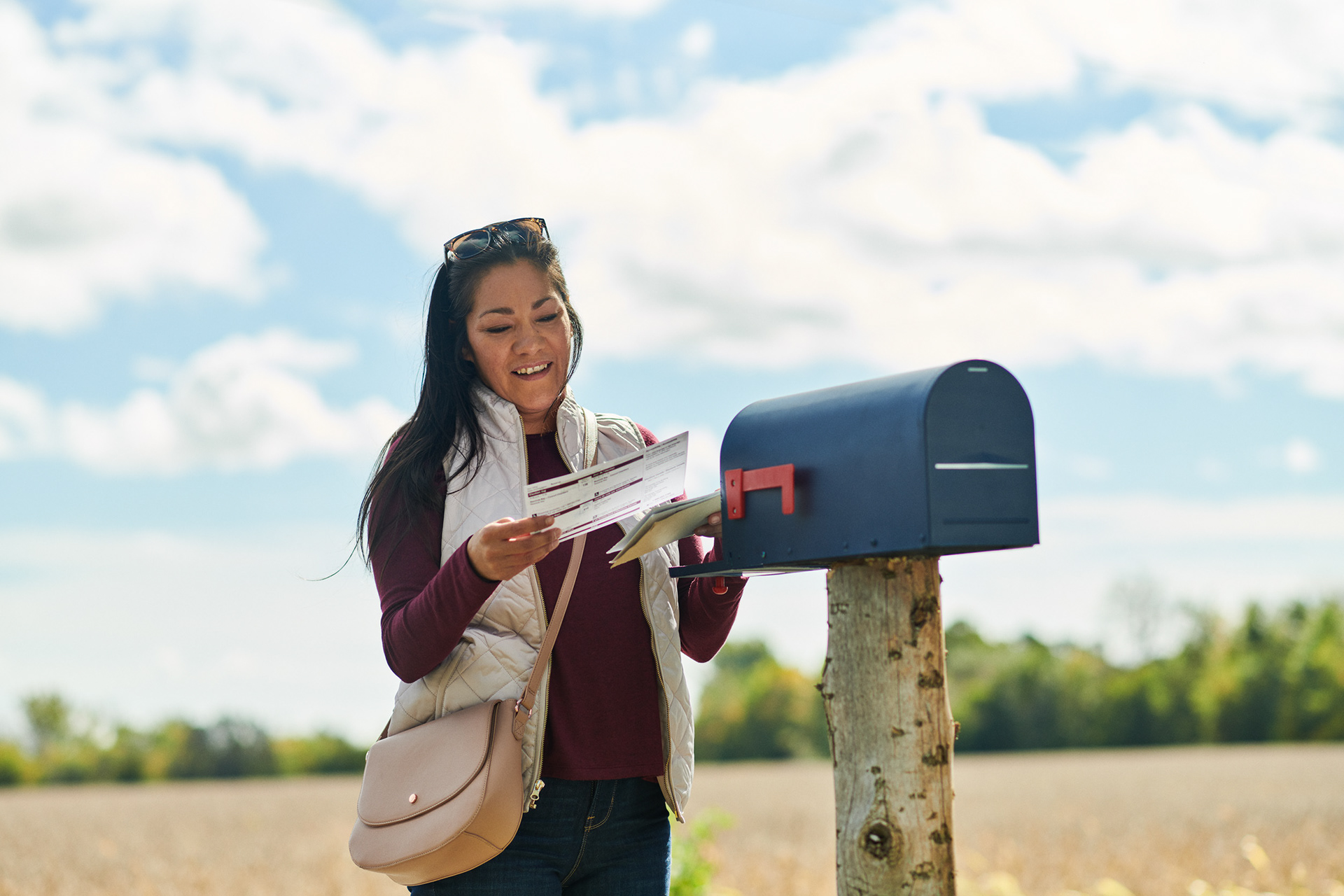 a rural aboriginal woman receives her mail in a mailbox by the side of the road in the country