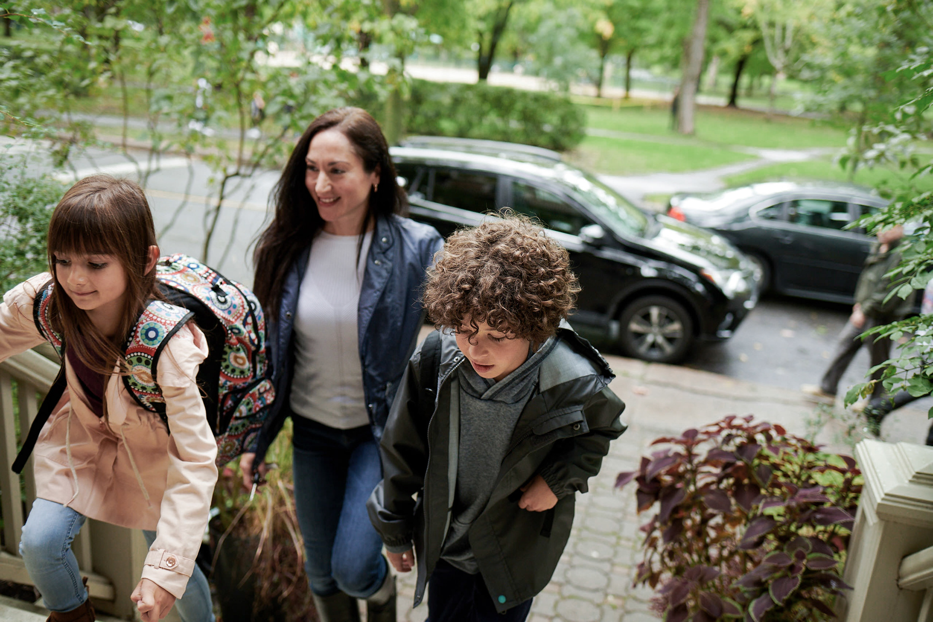a model mother walks up the stairs wirth her son and daughter coming back from school on a cloudy day