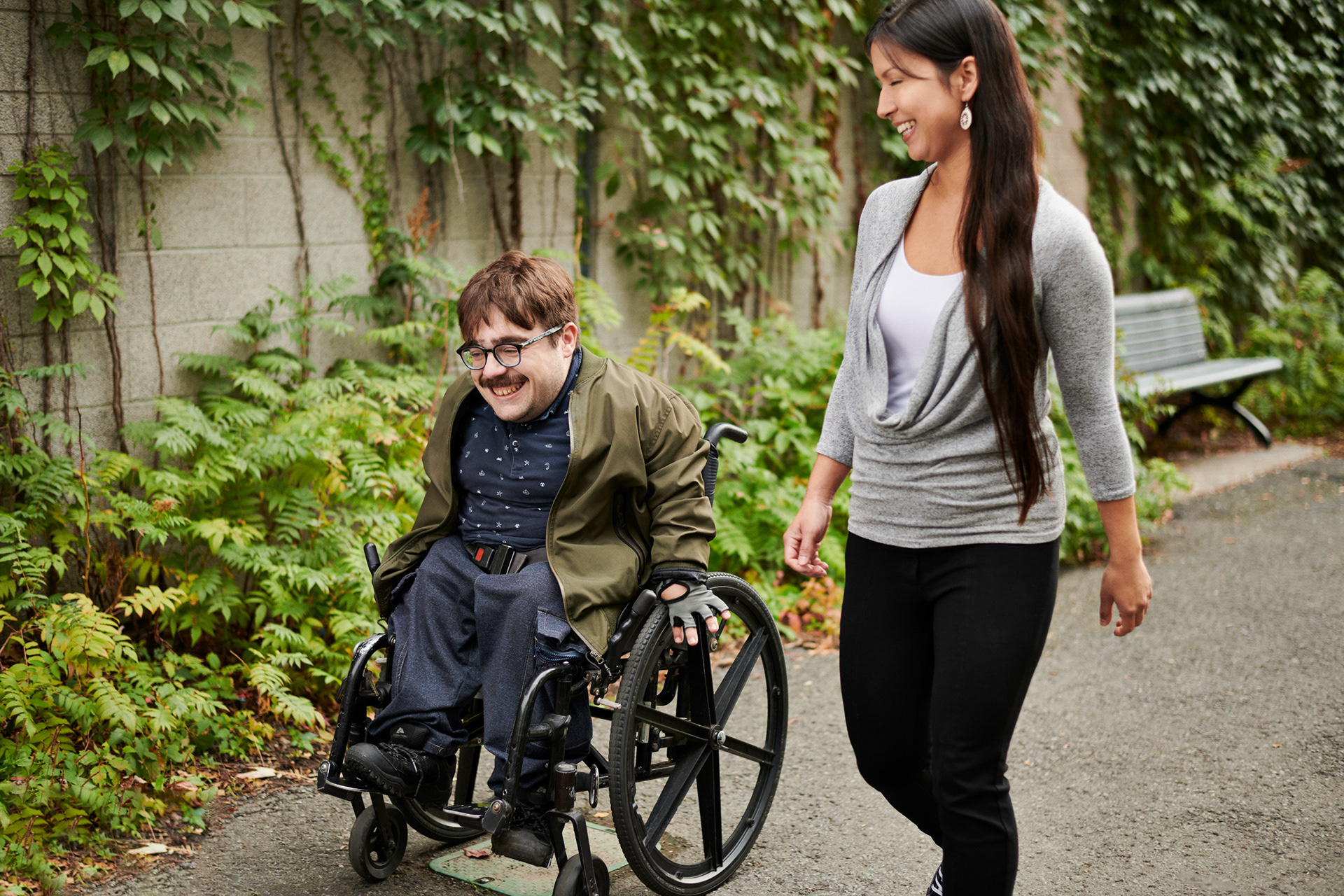 a young man in a wheelchair  and teenager walk to a destination