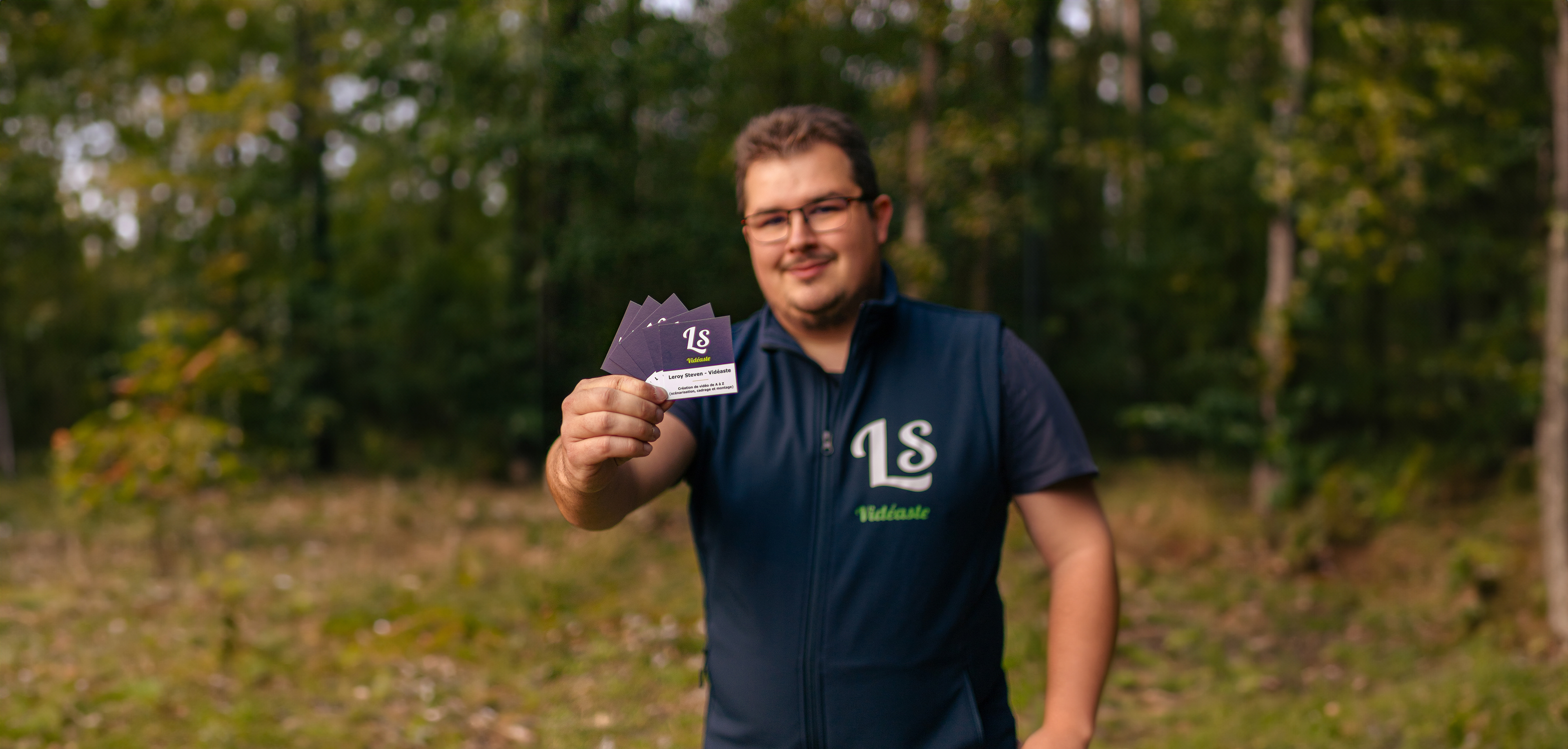 Photographie de Leroy Steven tenant fièrement ses cartes de visite. La mise au point est minutieusement réalisée sur les cartes, créant un effet de flou artistique autour. Cette image illustre ma préparation professionnelle et mon engagement envers la communication visuelle.