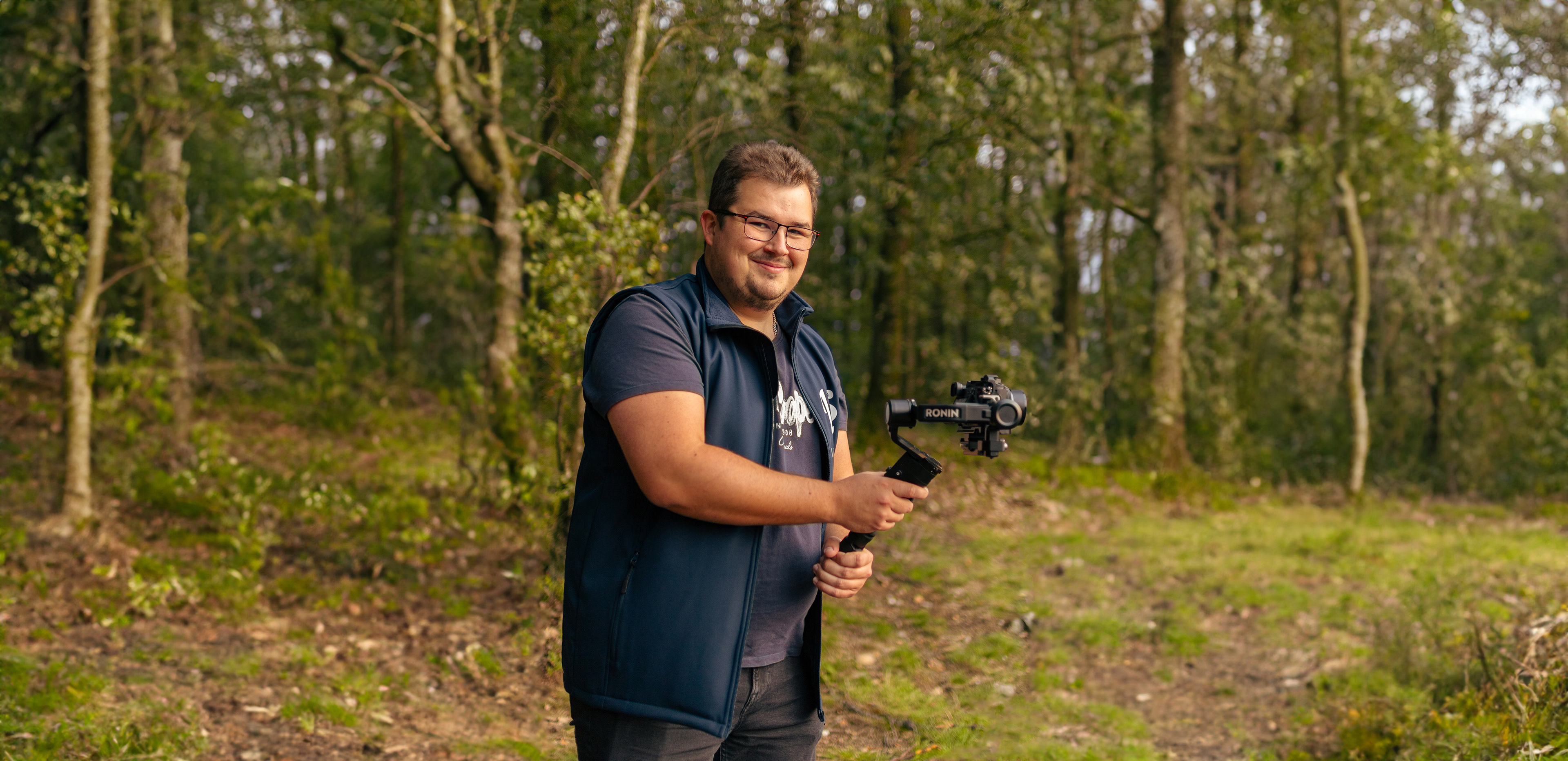 Photographie de Leroy Steven en action, équipé de son matériel professionnel. Il tient sa caméra montée sur un stabilisateur, prêt à capturer des moments mémorables. Cette image reflète mon engagement envers la qualité et la créativité dans mon travail en tant que vidéaste et photographe freelance.
