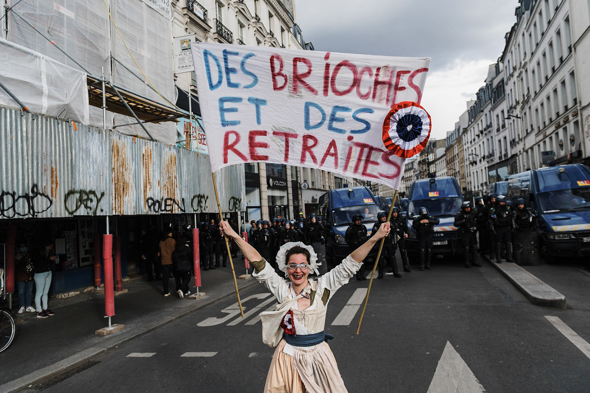 A protester holding a sign "Buns and pensions", dressed as a revolutionary woman. Protesters take part in a demonstration on the 12th day of action after the government pushed a pensions reform through parliament without a vote, using the article 49.3 of the constitution, in Paris, on April 13, 2023. France faced nationwide protests and strikes on April 13, 2023, to denounce the French government's pension reform on the eve of a ruling from France's Constitutional Council on the reform.