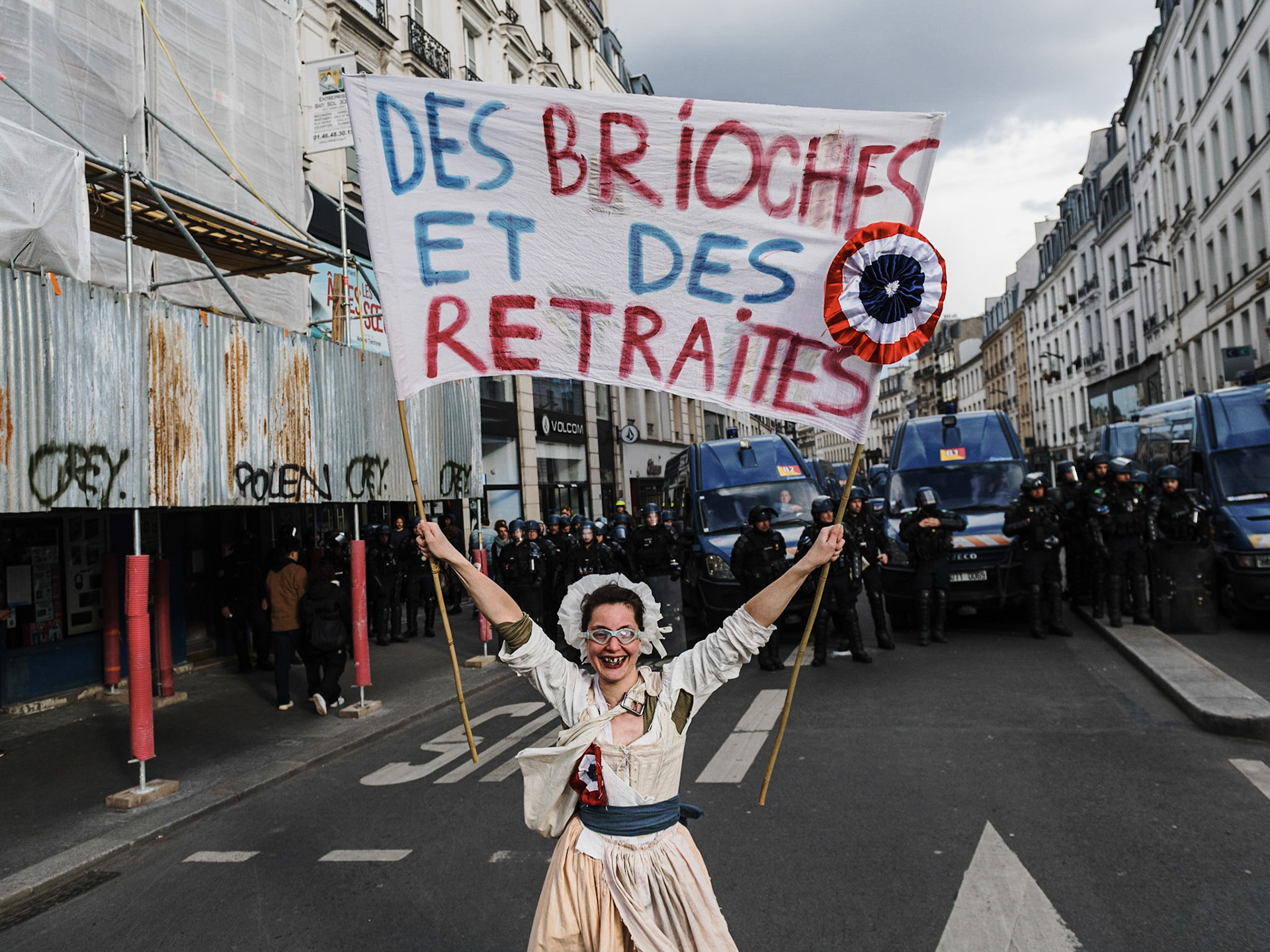 A protester holding a sign "Buns and pensions", dressed as a revolutionary woman. Protesters take part in a demonstration on the 12th day of action after the government pushed a pensions reform through parliament without a vote, using the article 49.3 of the constitution, in Paris, on April 13, 2023. France faced nationwide protests and strikes on April 13, 2023, to denounce the French government's pension reform on the eve of a ruling from France's Constitutional Council on the reform.