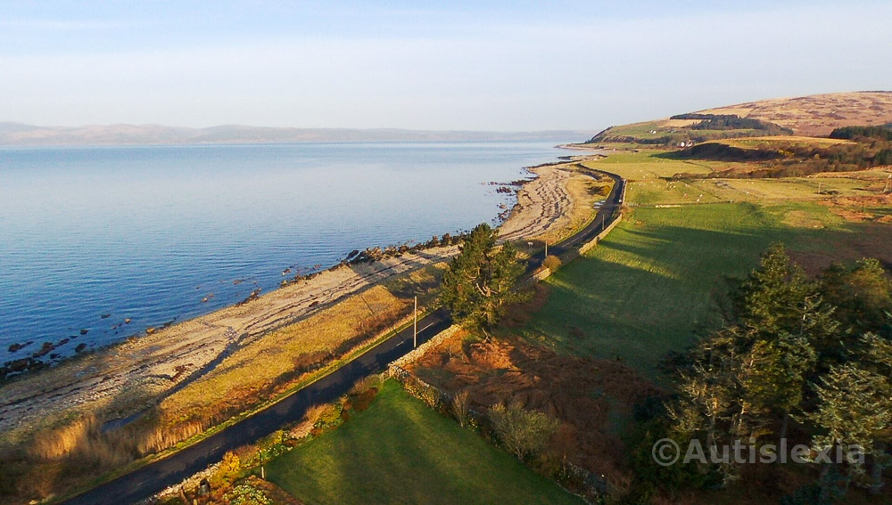 Arran coastline, Isle of Arran, narrow road going off into the distance, with the pebble beach and sea on the left and the land on the right.