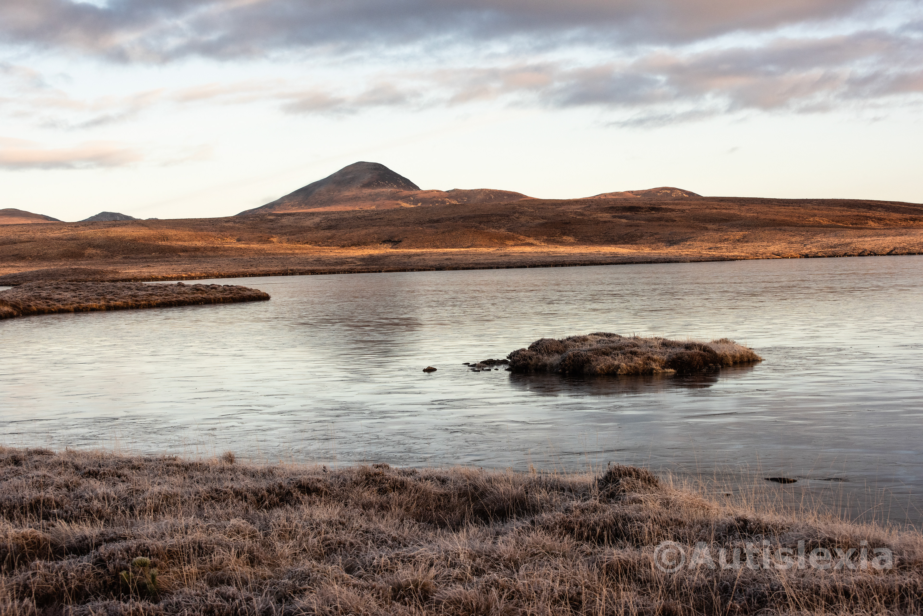 Frosty scenery with a Loch with a very small island just off the shore and a mountain in the background