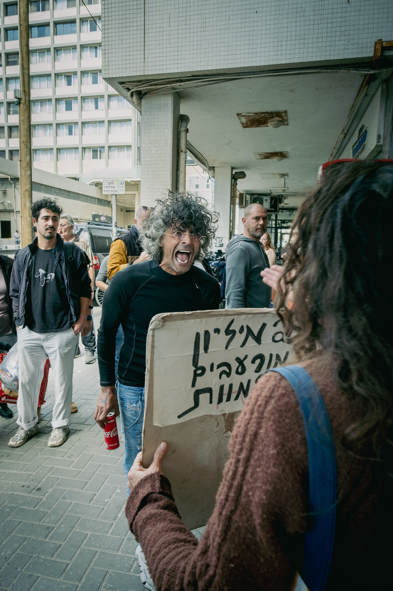An angry pedestrian screaming at a protestor holding a sign: "2 Million starved to death". Tel Aviv - 8 March 2024