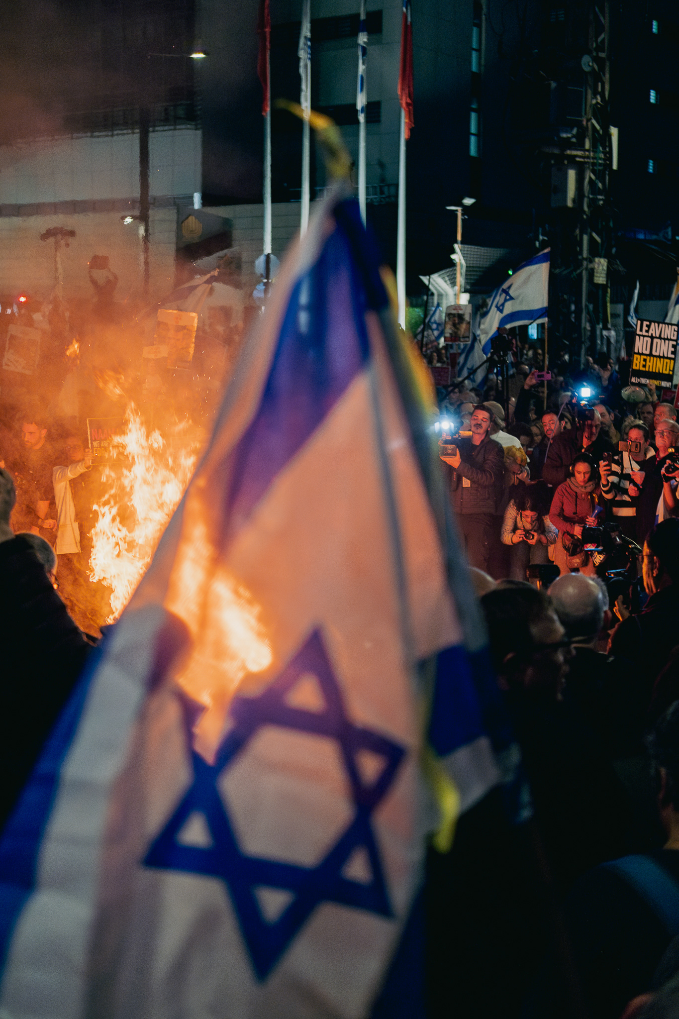 Protestors set fire in front of Begin Gate of the Kirya, an Israeli flag in the foreground. Tel Aviv - 16 March 2024
