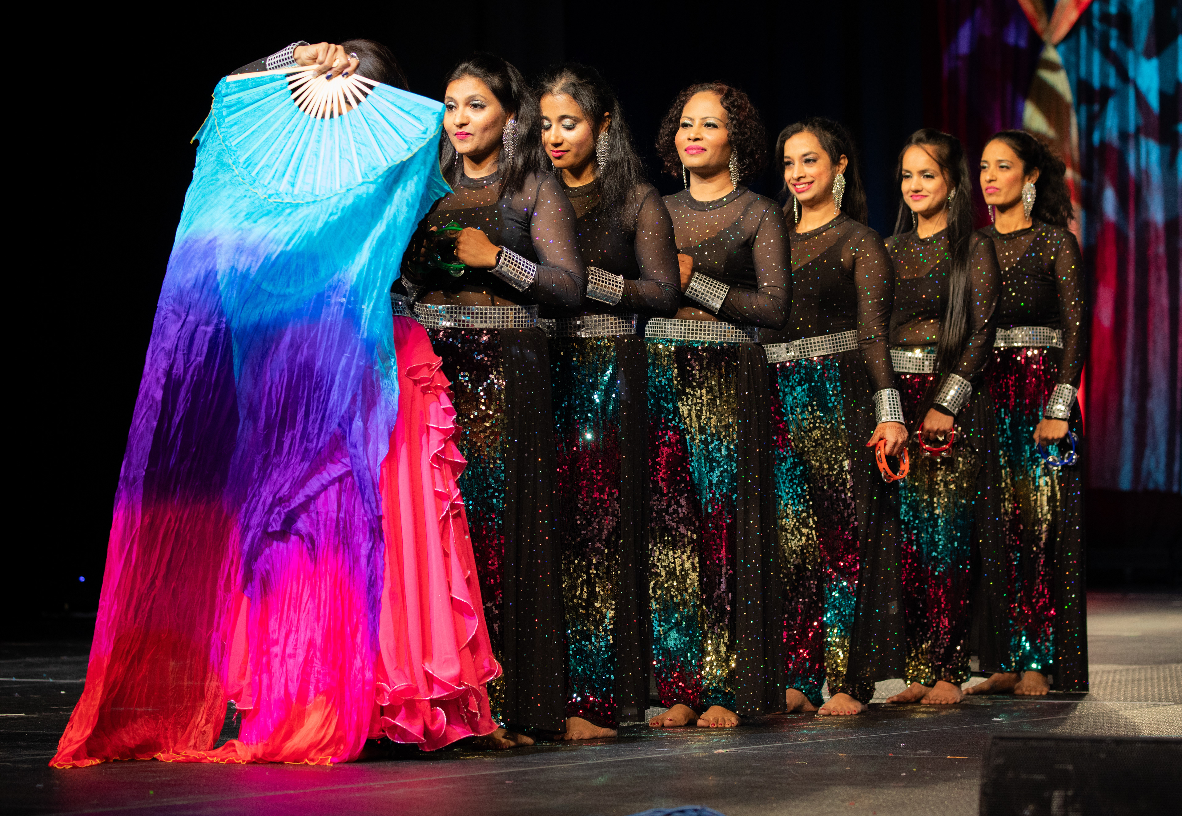 As the curtain rises, a tapestry of anticipation unfolds. The lead dancer, a maestro of motion, weaves vibrant hues into the air, setting the stage ablaze with anticipation. The group stands in unity, ready to embrace the rhythm that awaits.