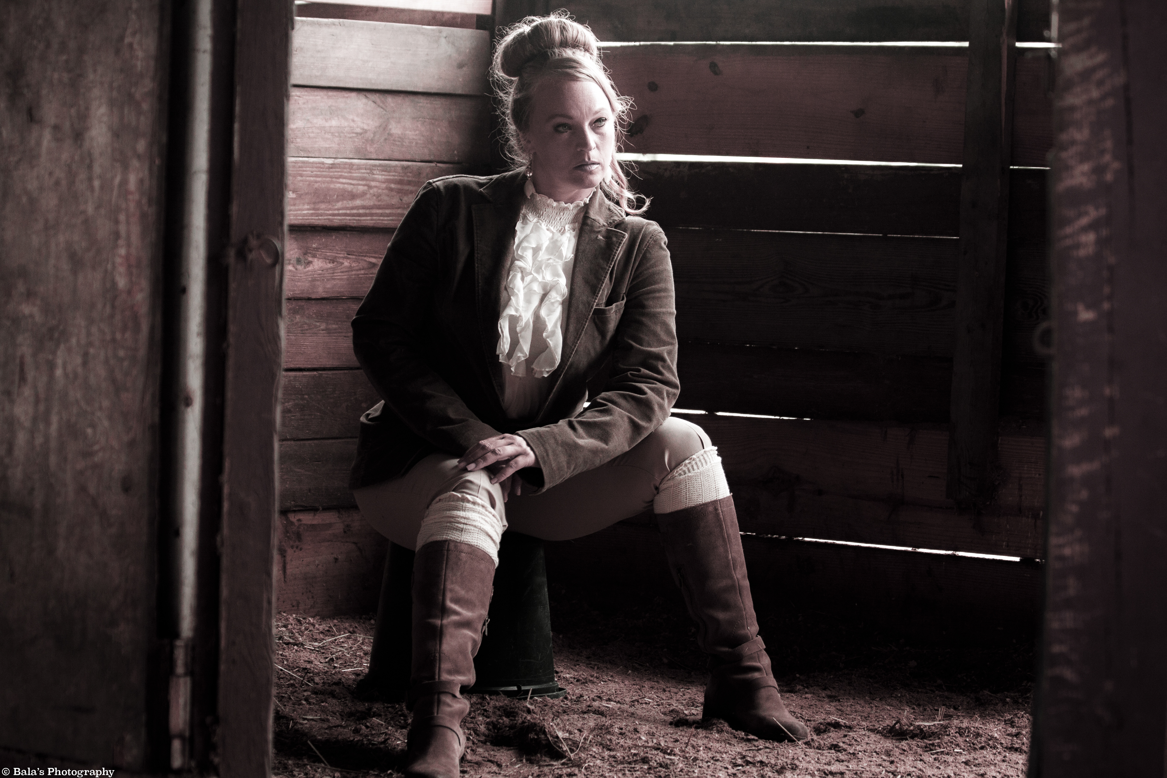 In the rustic embrace of a horse barn, she transforms into a cowgirl, perched within a stall. Her gaze pierces the unseen horizon, a portrait of concentration and untamed determination. In the echo of hooves and creaking wood, she channels the spirit of the Wild West, her eyes revealing a tale untold.