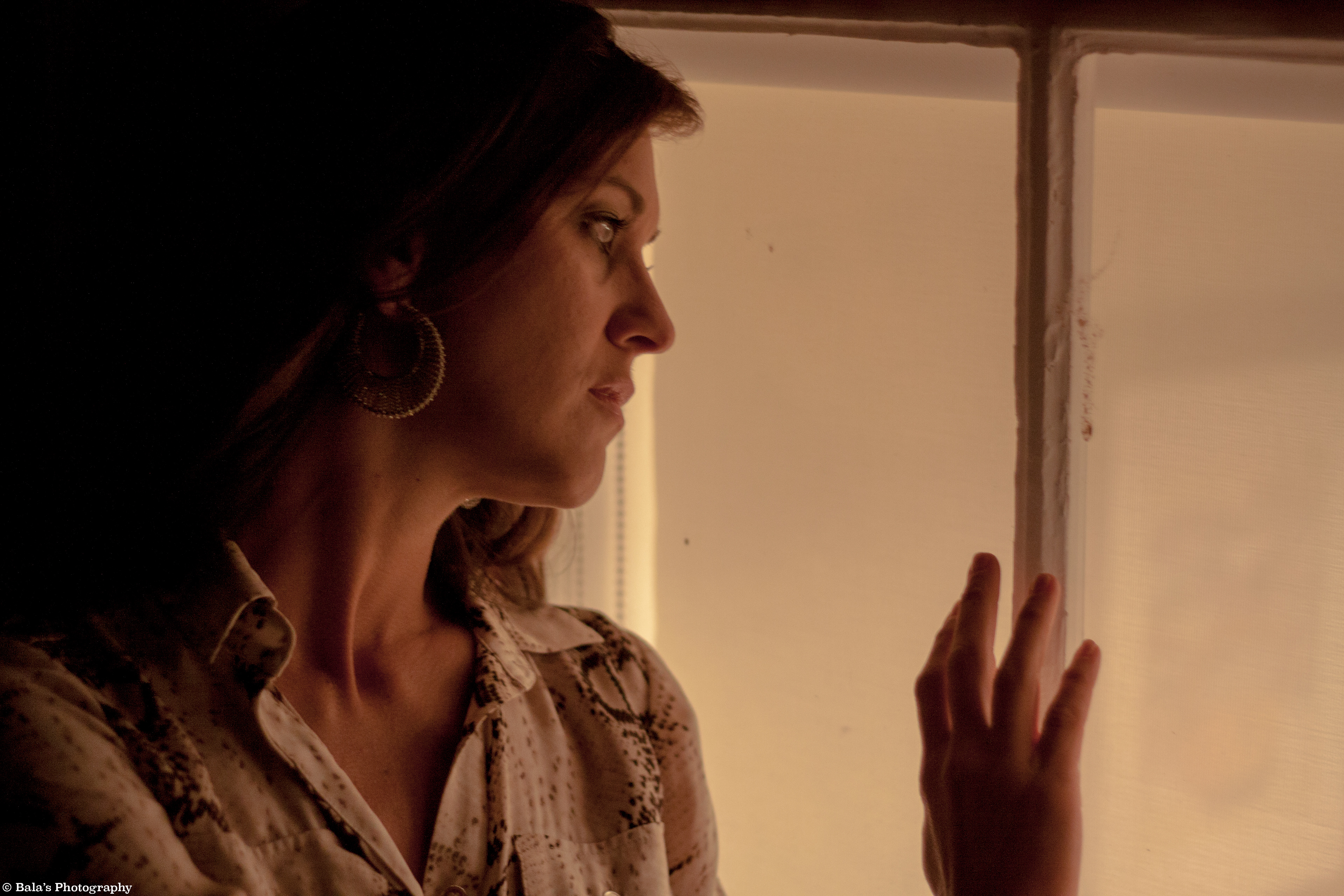 Her gaze fixated on the window, intensity in her eyes reveals a silent narrative. No expression, just a captivating curiosity, as if the glass holds secrets, and she's drawn into an intriguing story unfolding beyond, a moment suspended in the night's enigmatic charm.