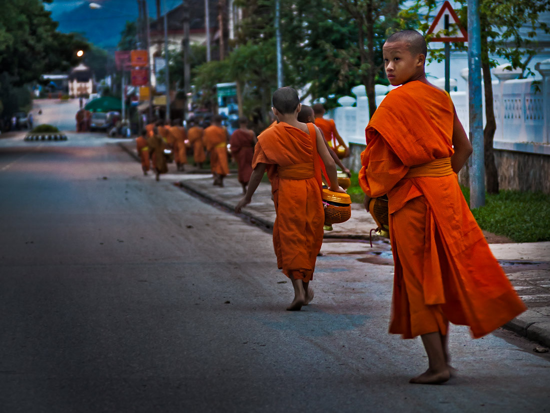 Early morning in Luang Prabang, Laos. Young monks are out on their daily rounds collecting food from villagers.