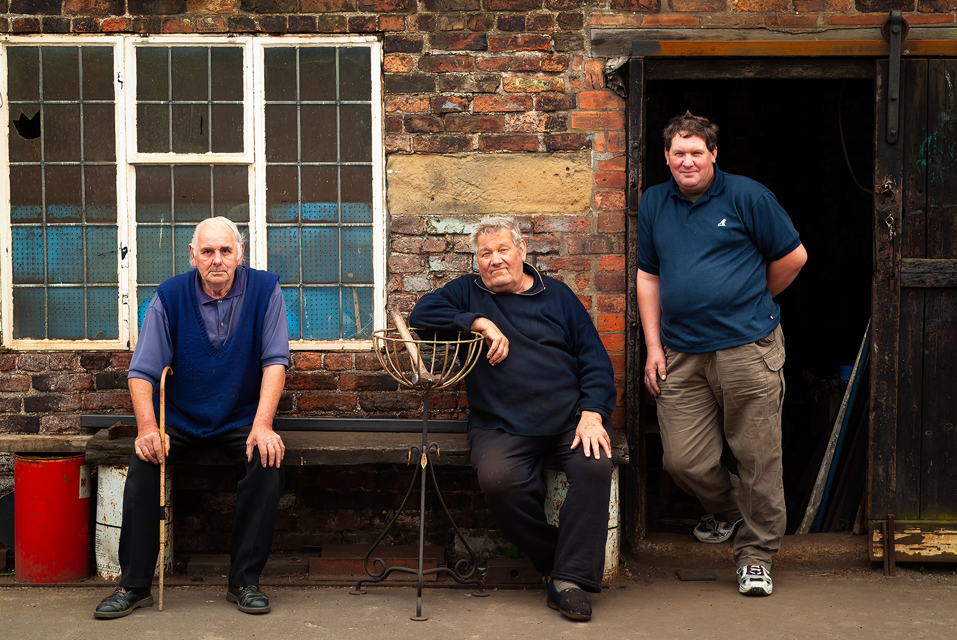 The Blacksmith and his apprentice take a break at the forge to chew the fat with a resident (left)  Laxton Village Blacksmiths Forge, Laxton, East Yorkshire, United Kingdom, 07 July 2004.   Fuji FinePix S2