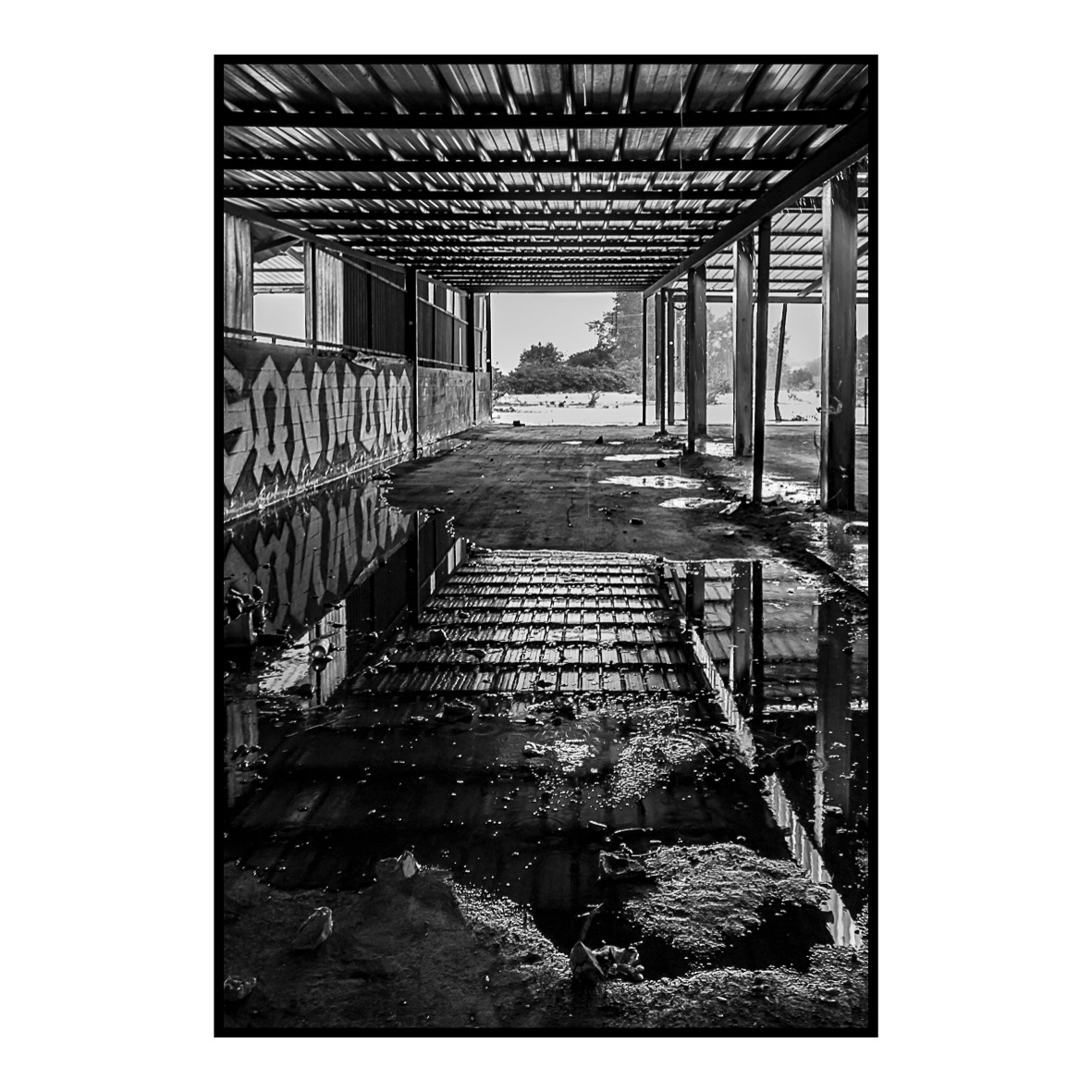 7. A l’abri de la pluie (juillet 2017) … une vision furtive qui me guide. Sur le retour de mon magasin photo favori, je décide de flâner et ne pas prendre l’itinéraire habituel. Je lève le pied et prends tout le temps de regarder autour de moi. En une fraction de seconde, j’aperçois en contrebas un ancien site industriel abandonné avec un immense hangar en son milieu. Je m’engouffre dans une rue, puis une seconde, tourne encore quelques instants avant de trouver un parking à proximité du lieu. A cet instant le ciel est très menaçant et l’orage gronde au loin. Comme à mon habitude, j’ai mon appareil avec moi. Je déballe frénétiquement le matériel que je viens d’acheter et saisi mon sac photo. Plus que quelques mètres et j’arrive à proximité du hangar. La pluie se met à tomber finement, je commence à faire le tour du site et faire quelques clichés. Après quelques minutes, c’est une pluie torrentielle qui s’abat sur les tôles provoquant un véritable vacarme. Le toit a perdu une majeure partie de son étanchéité et de nombreuses flaques se forment alors au sol. L’orage est désormais au-dessus de moi ! Je contemple béat cette myriade de flaques qui se constitue autour de moi, puis, mon regard se fige sur un reflet dans l’une d’entre elles. Je me baisse légèrement afin de construire mon image et trouver le meilleur angle pour photographier le reflet du toit. Les conditions sont de plus en plus épouvantables et la pluie ruisselle désormais dans mon dos. Je fais quelques images qui ne me conviennent pas. Je fais une nouvelle série en mode rafale car je veux capturer l’instant où une goutte vient fracasser le sol et disparait dans de multiples projections. L’obturateur de mon boîtier crépite et vient saisir au vol les éclaboussures tant attendues.